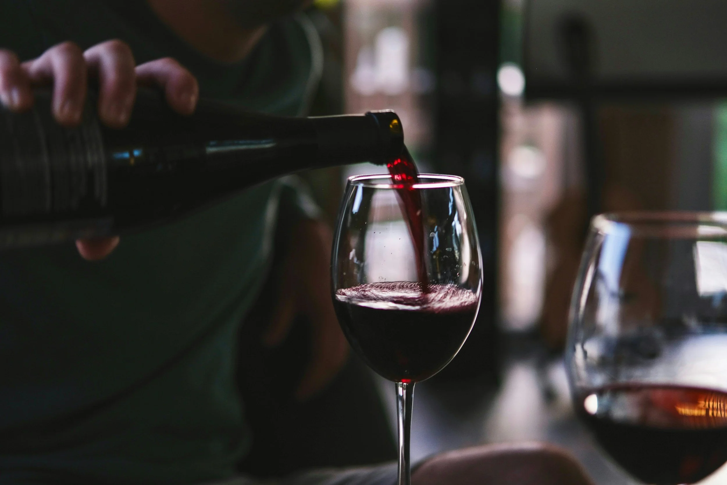 Red wine being poured into a glass during a restaurant wine service