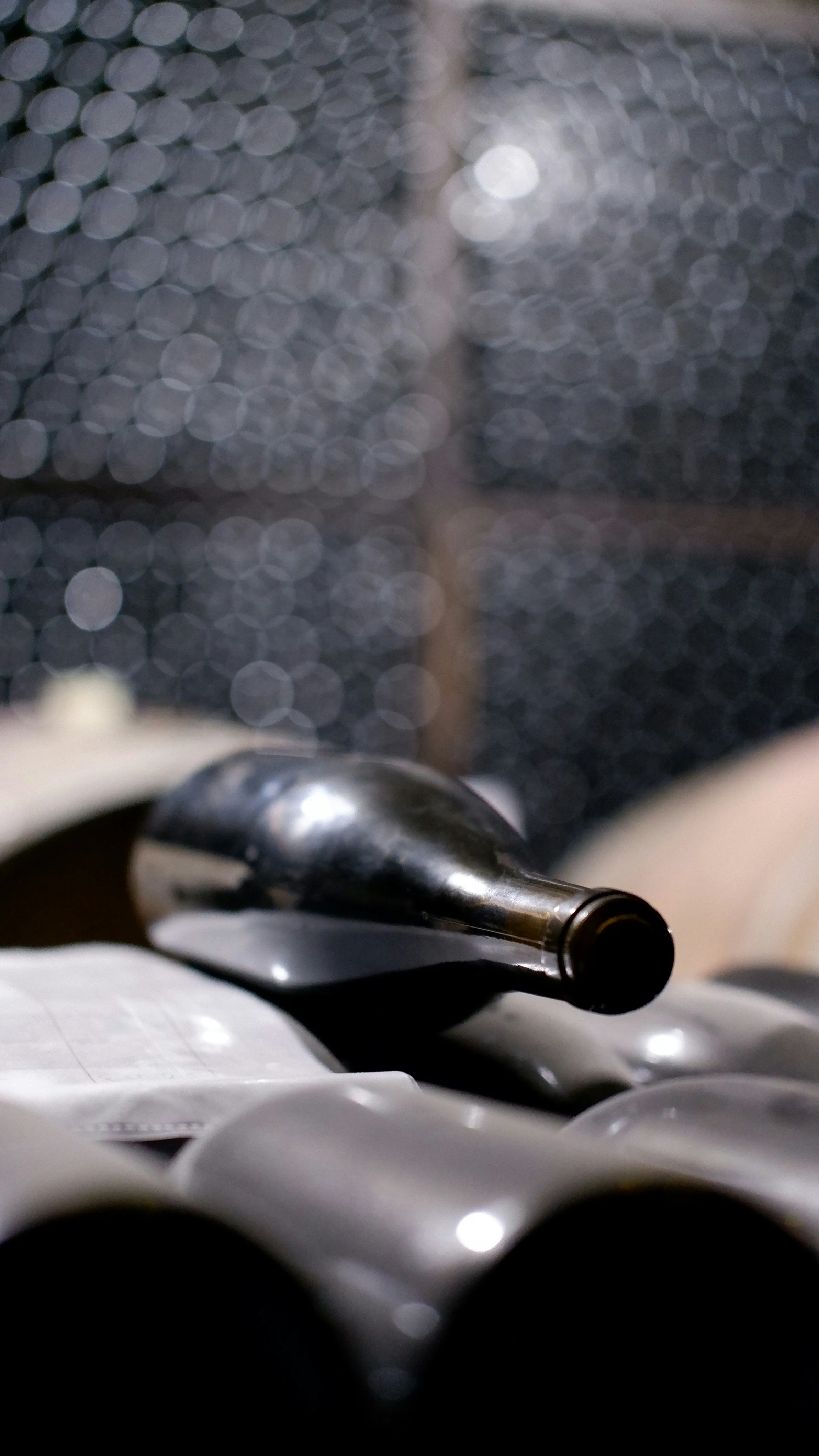 Older wine bottle resting in a cellar rack, representing the unexpected discovery of a forgotten bottle of wine.