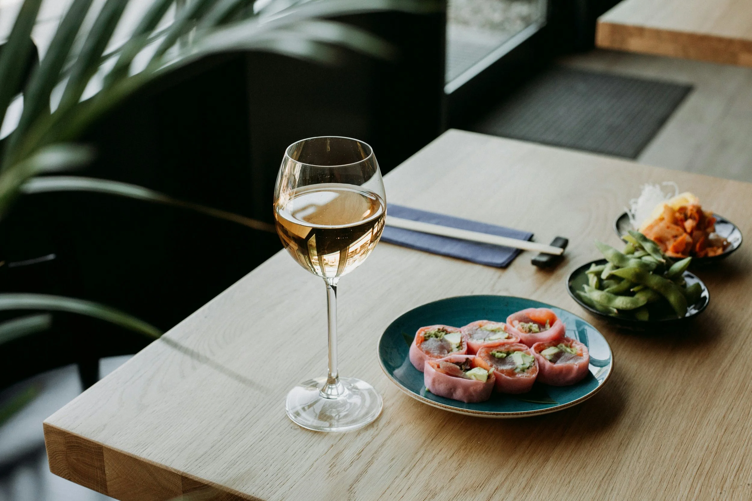 Glass of Chablis wine served with sushi and small plates, highlighting the crisp acidity and food-friendly nature of Chablis Chardonnay from Burgundy, France.