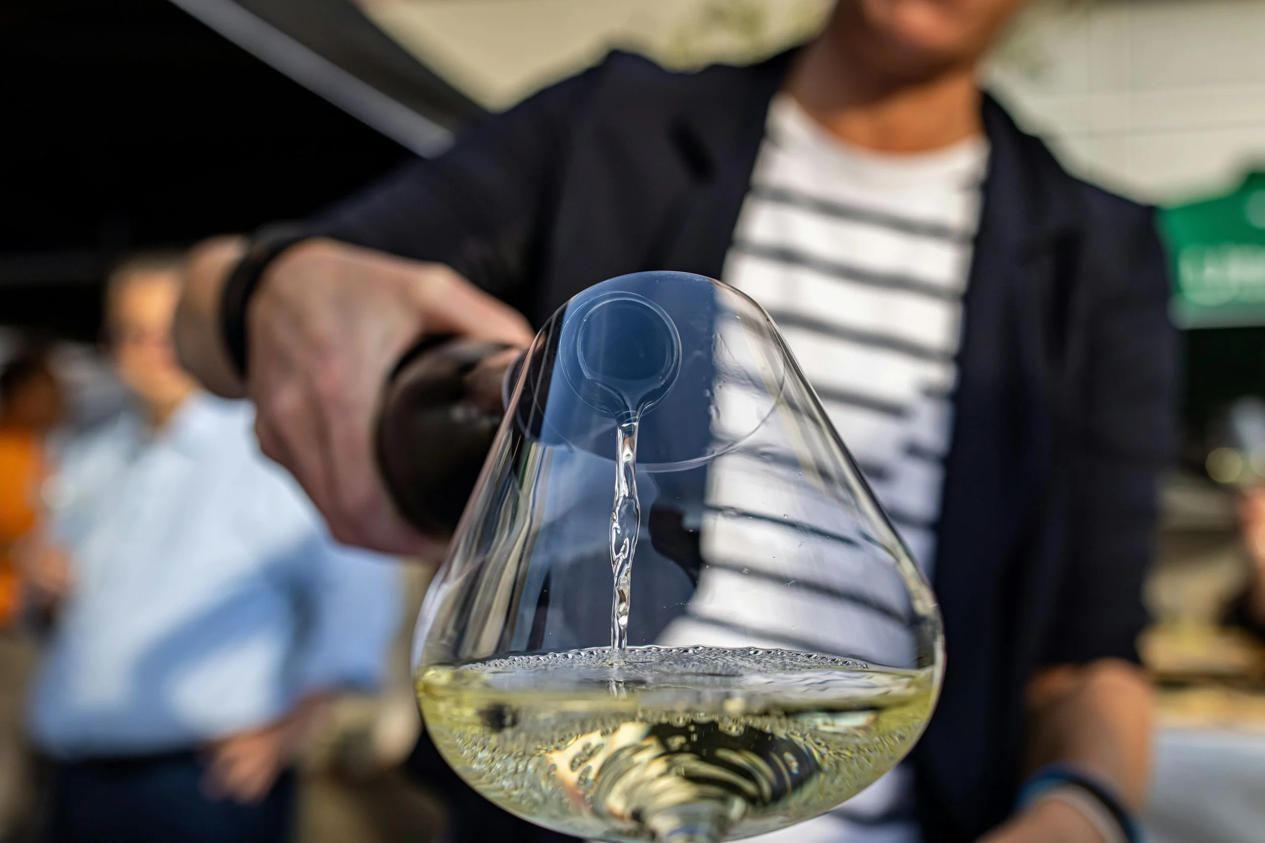 White wine being poured into a tasting glass during a guided wine tasting experience led by a wine professional.