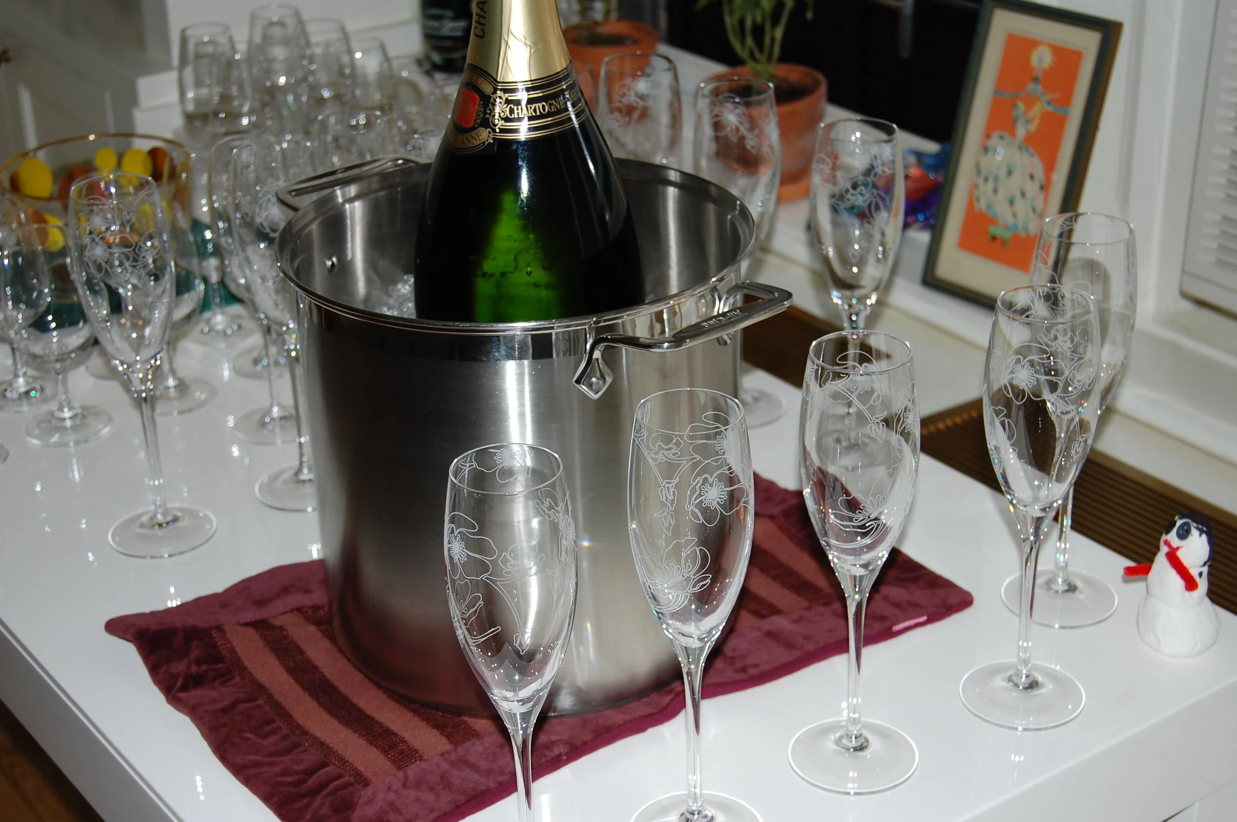 Champagne bottle in an ice bucket with water and ice surrounded by glasses, demonstrating proper wine chilling and serving temperature