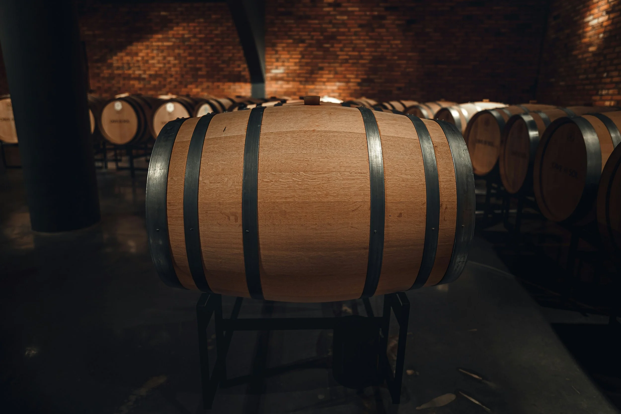 Large oak wine barrel in a winery cellar where wine is aged to develop flavor, texture, and complexity.