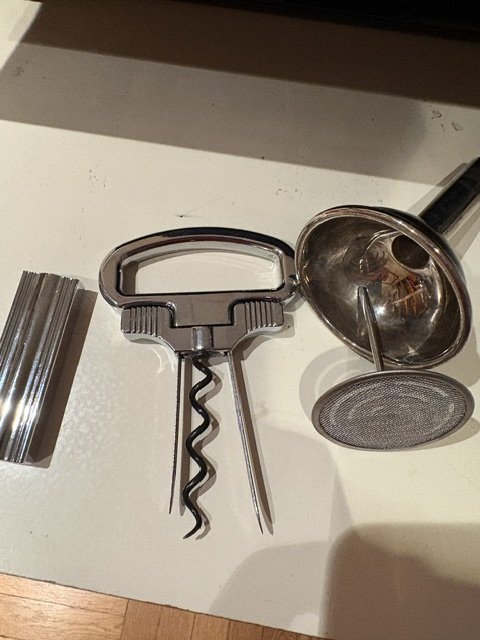 Wine opening tools including a corkscrew, funnel, and filter used when opening and serving older bottles of wine.