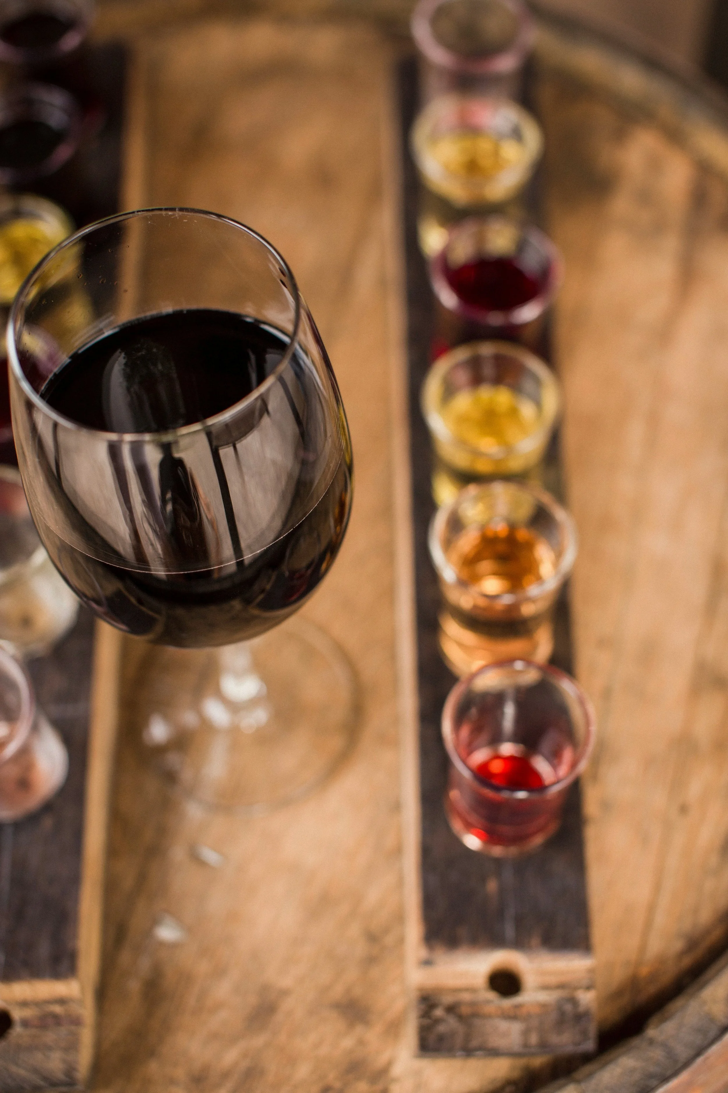 Glass of red wine alongside a tasting flight featuring multiple wine styles, illustrating wine evaluation and comparative tasting experiences.