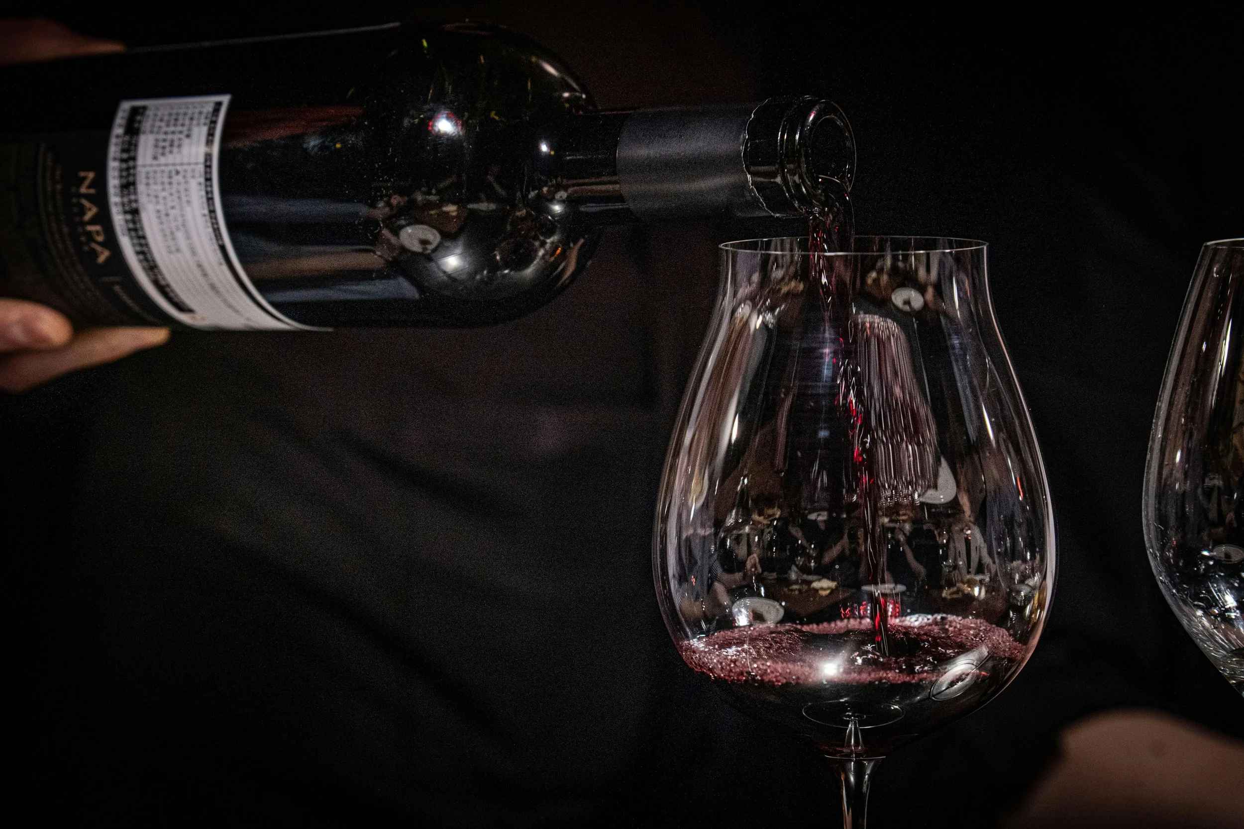 Red wine being poured into a tasting glass during a guided home wine tasting experience.