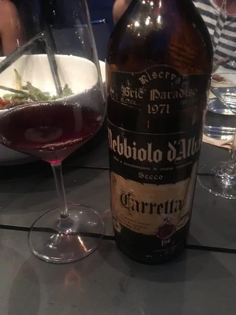 Bottle of Nebbiolo wine from Italy with a glass of red wine on a restaurant table, representing an affordable alternative to Barolo