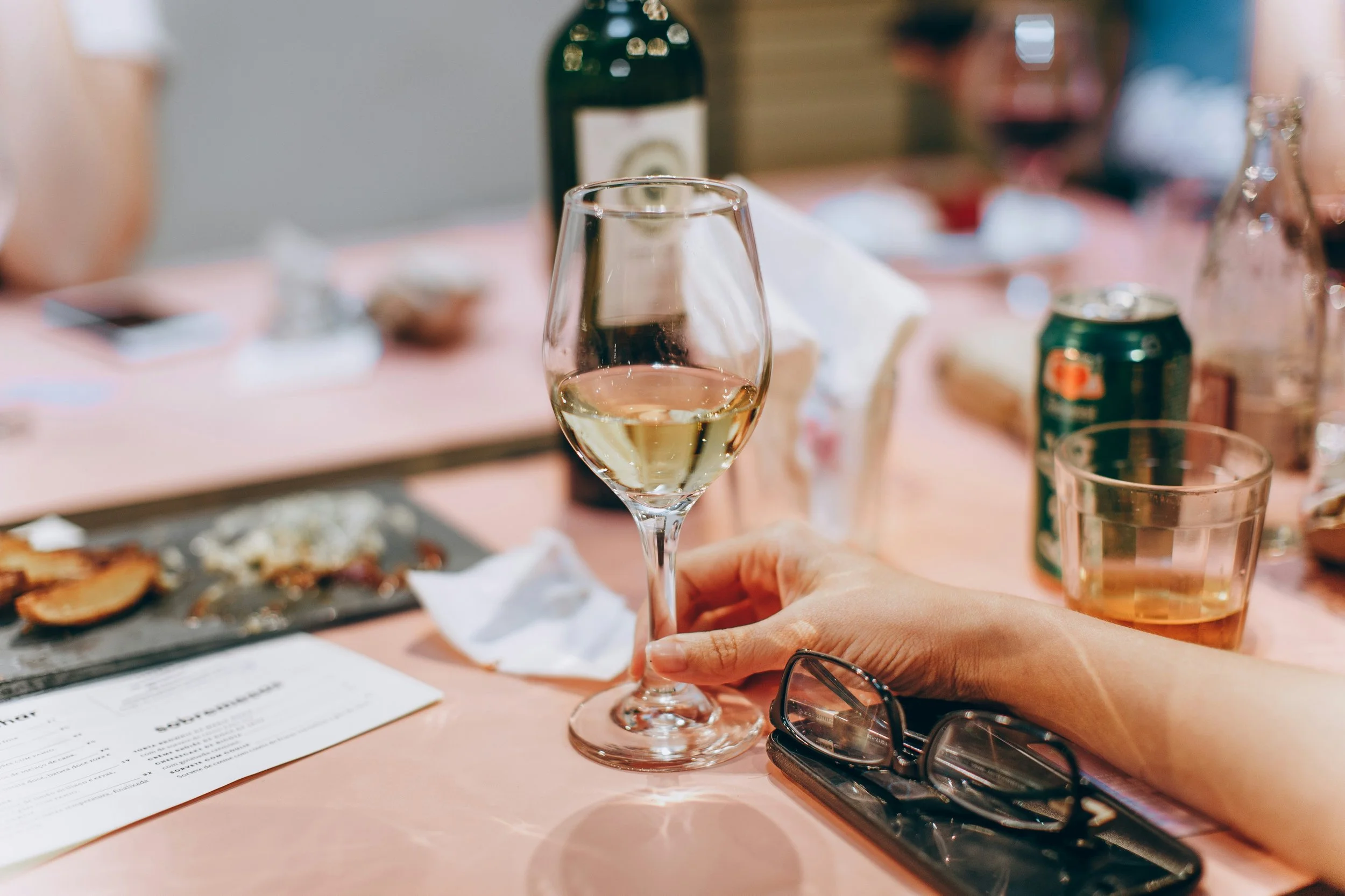 Guest holding a glass of white wine during a private wine tasting dinner experience with food pairings and a relaxed social atmosphere.