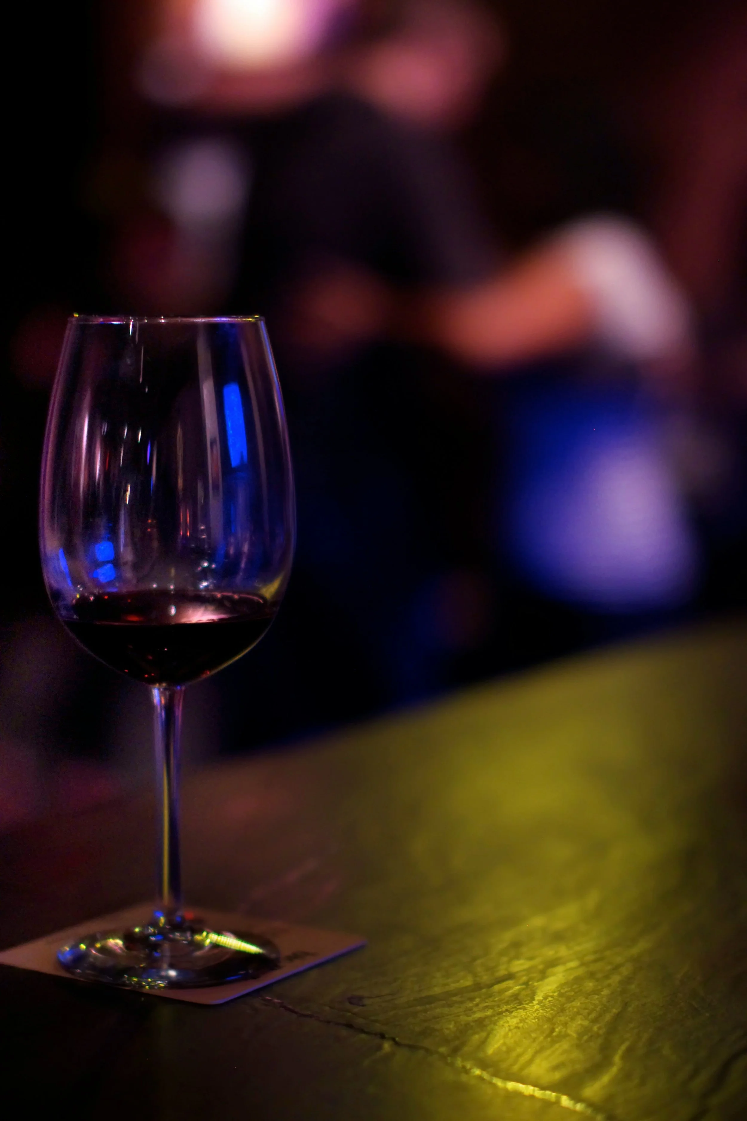Glass of red wine illuminated by warm ambient lighting, representing the unexpected quality and enjoyment of a well-aged Cabernet Sauvignon.