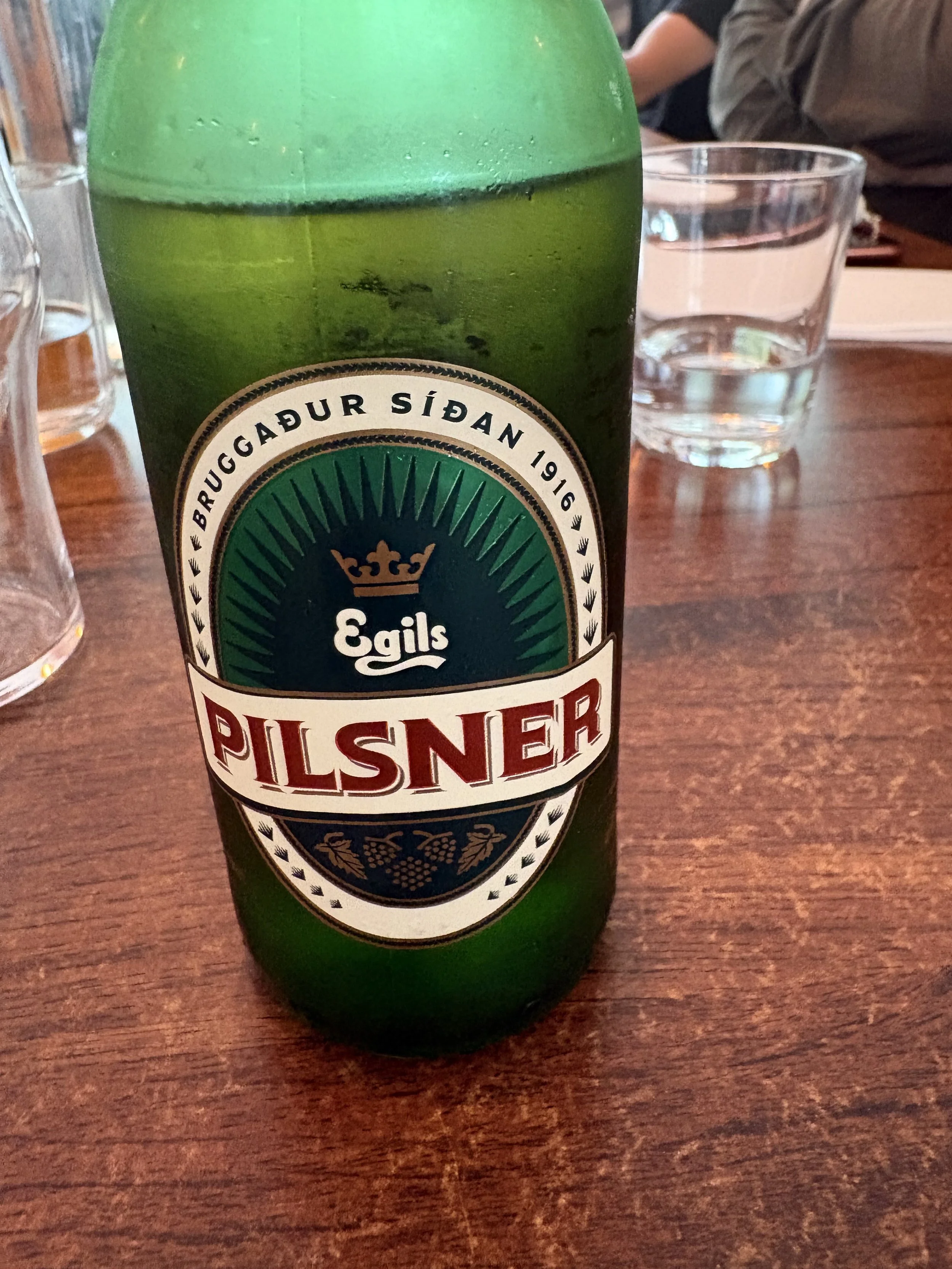 Bottle of Egils Pilsner beer served at a restaurant in Iceland, a classic pairing with Iceland's famous hot dogs.