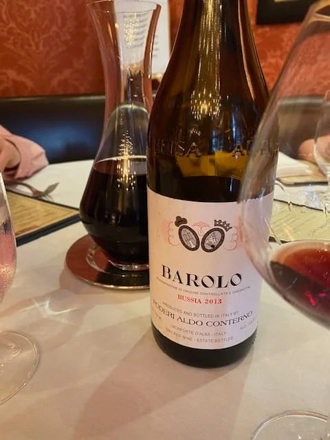 Barolo wine bottle by Aldo Conterno on a restaurant table with decanter and glasses, showcasing a premium Italian Nebbiolo wine