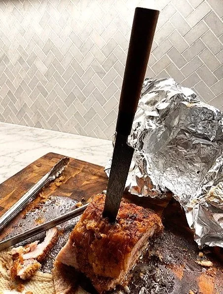 Porchetta on a cutting board with a chef's knife.