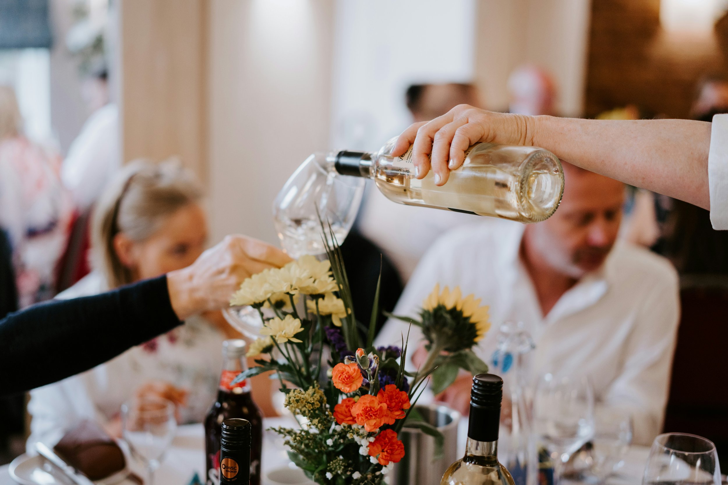 White wine being poured during a dinner gathering, highlighting the social and food-friendly experience of wine tasting and entertaining.