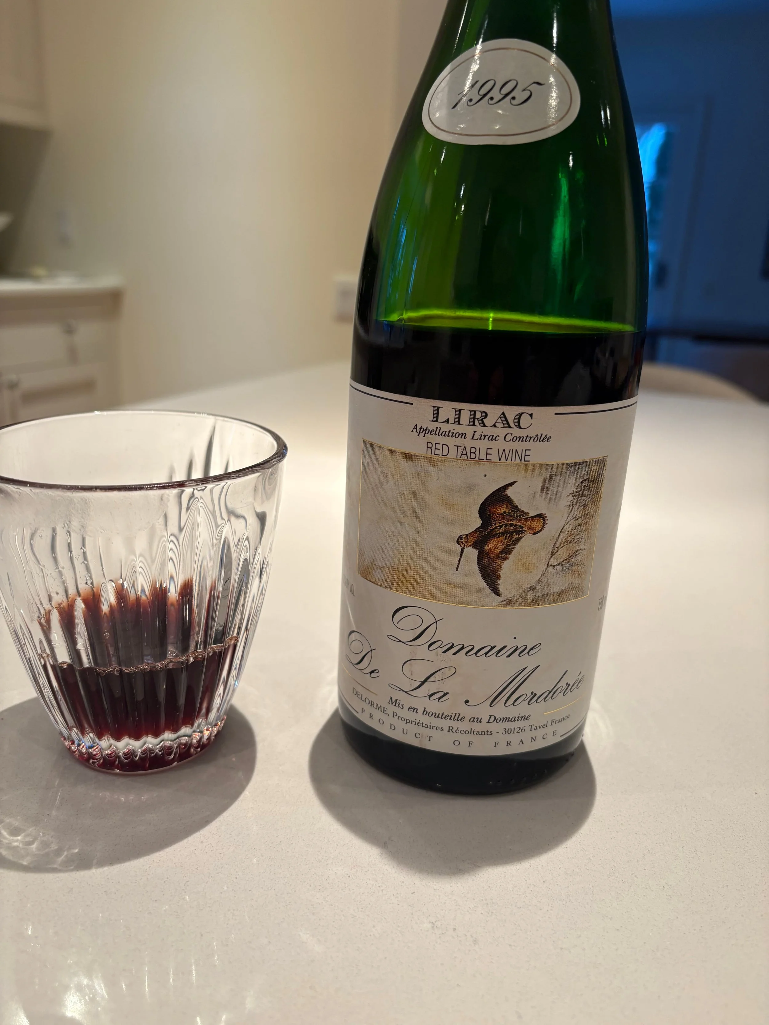 1995 Domaine de la Mordorée Lirac Rouge bottle beside a glass of red wine