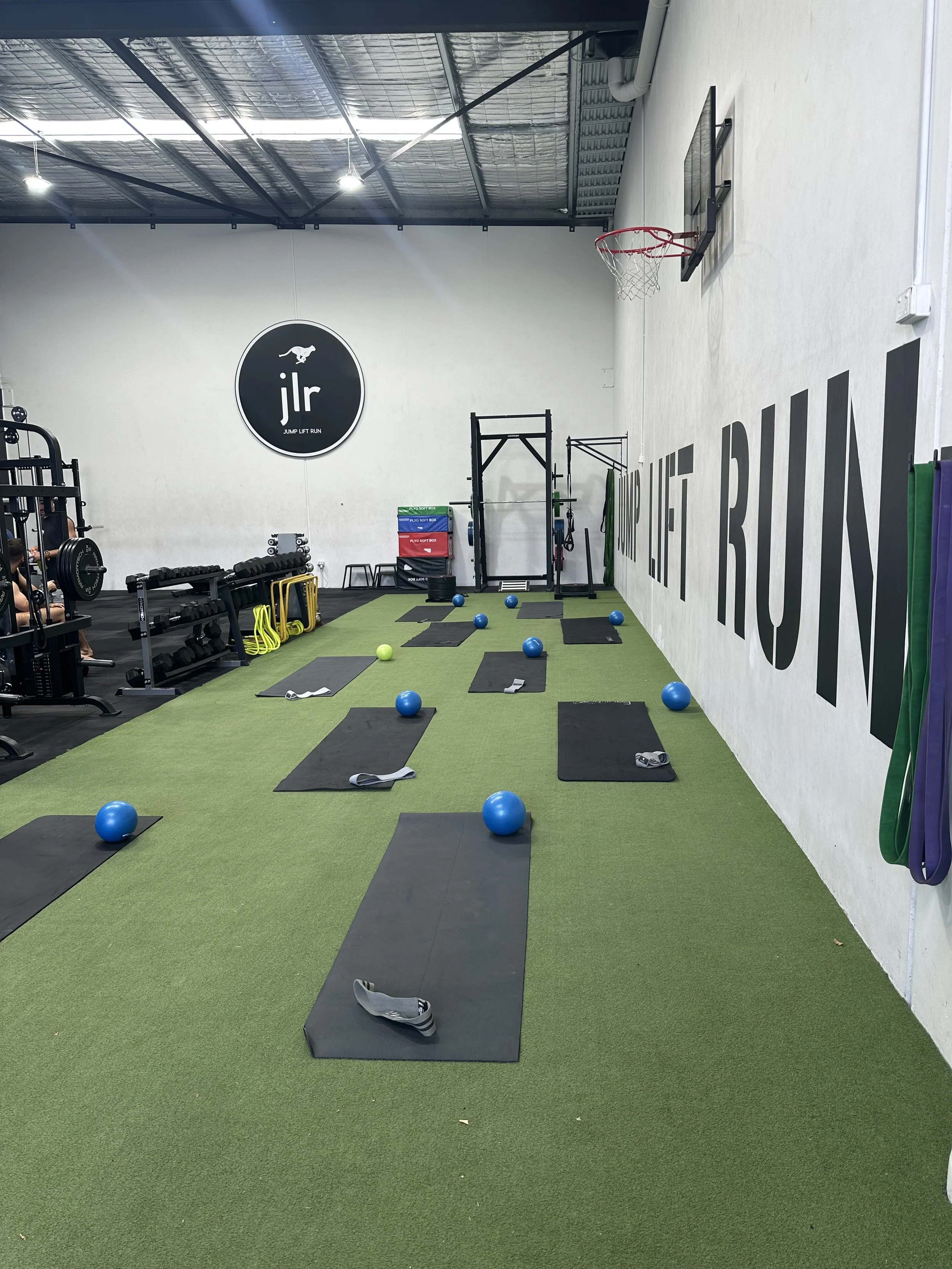 Fitness gym with exercise mats, resistance bands, medicine balls, dumbbells, and a pull-up station.