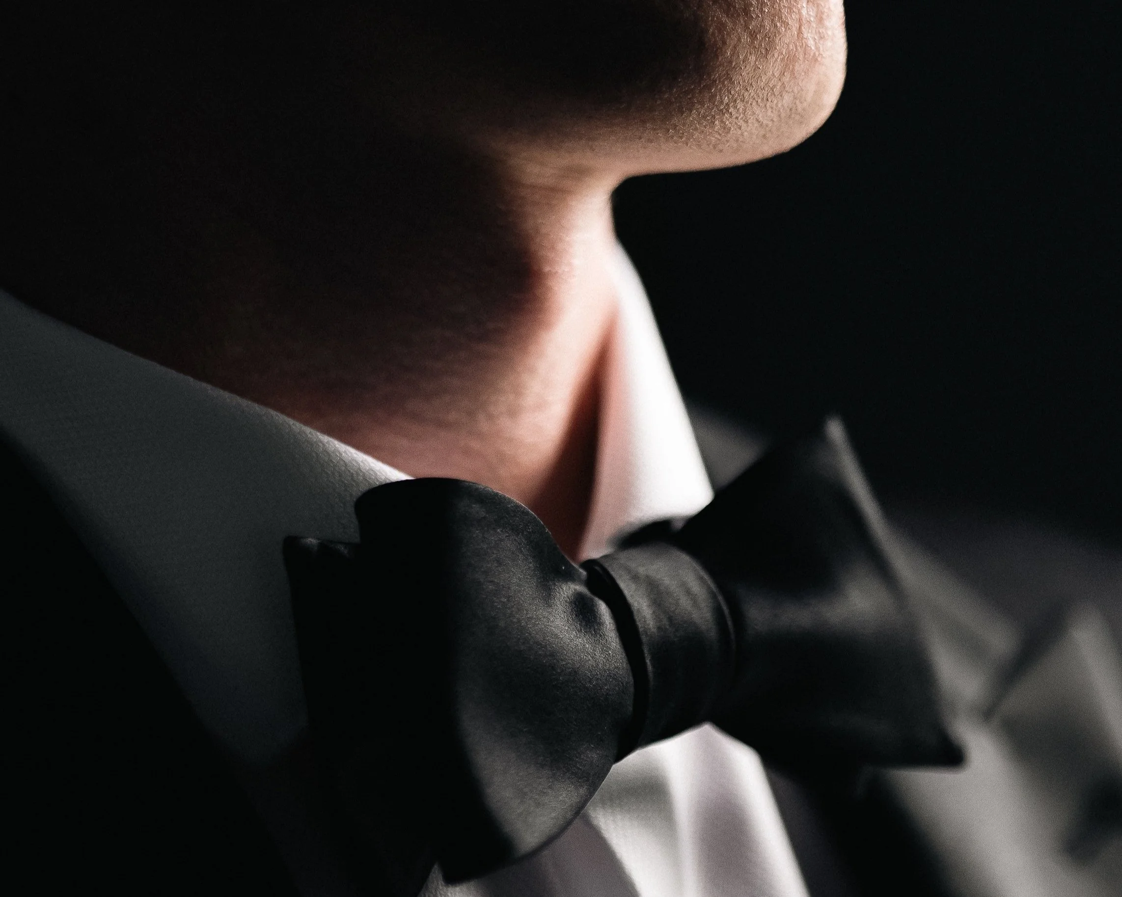 Close-up of a person wearing a black bow tie with a white shirt.