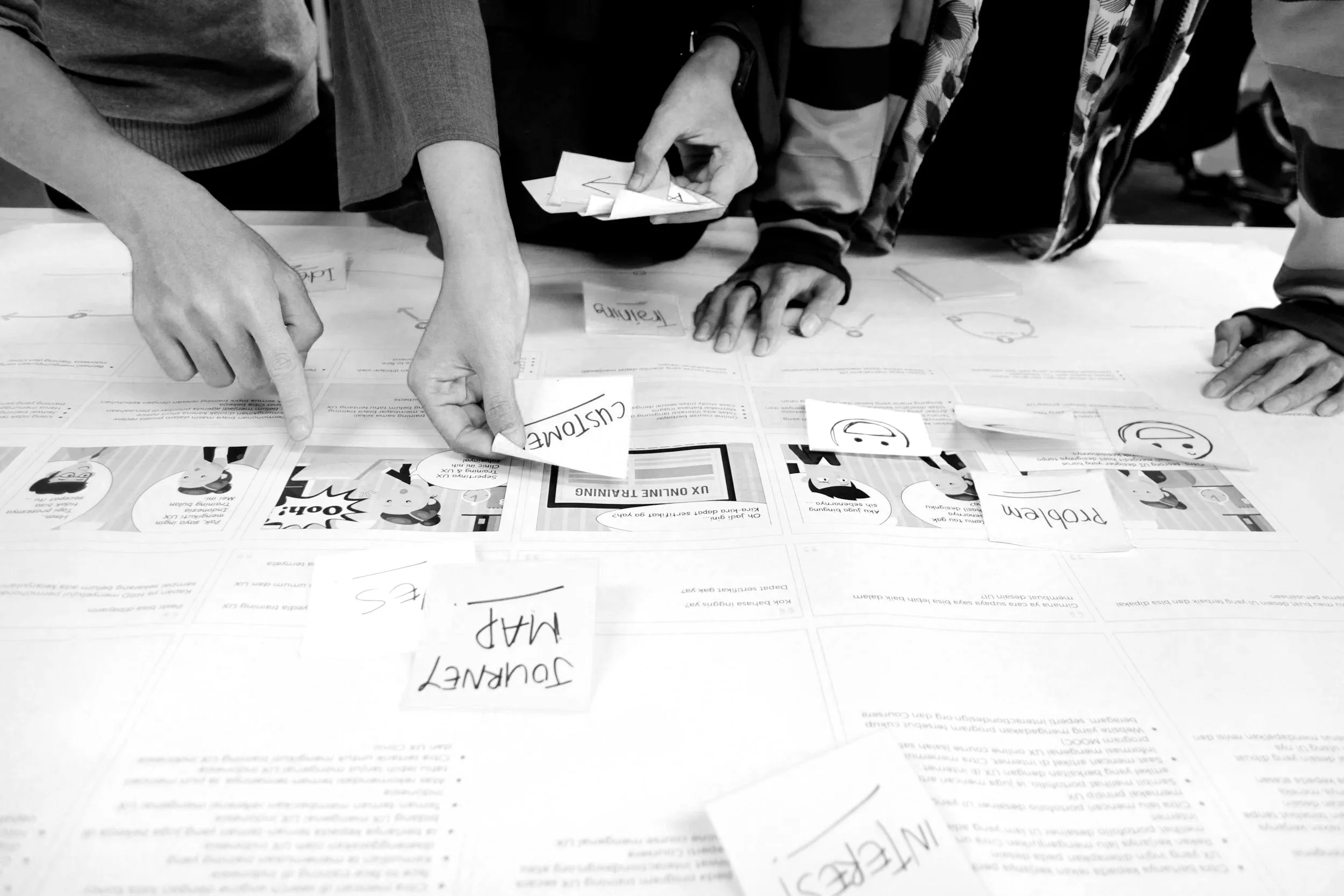 Group of people working on a planning document with colorful sticky notes and comic strips, pointing and discussing ideas.