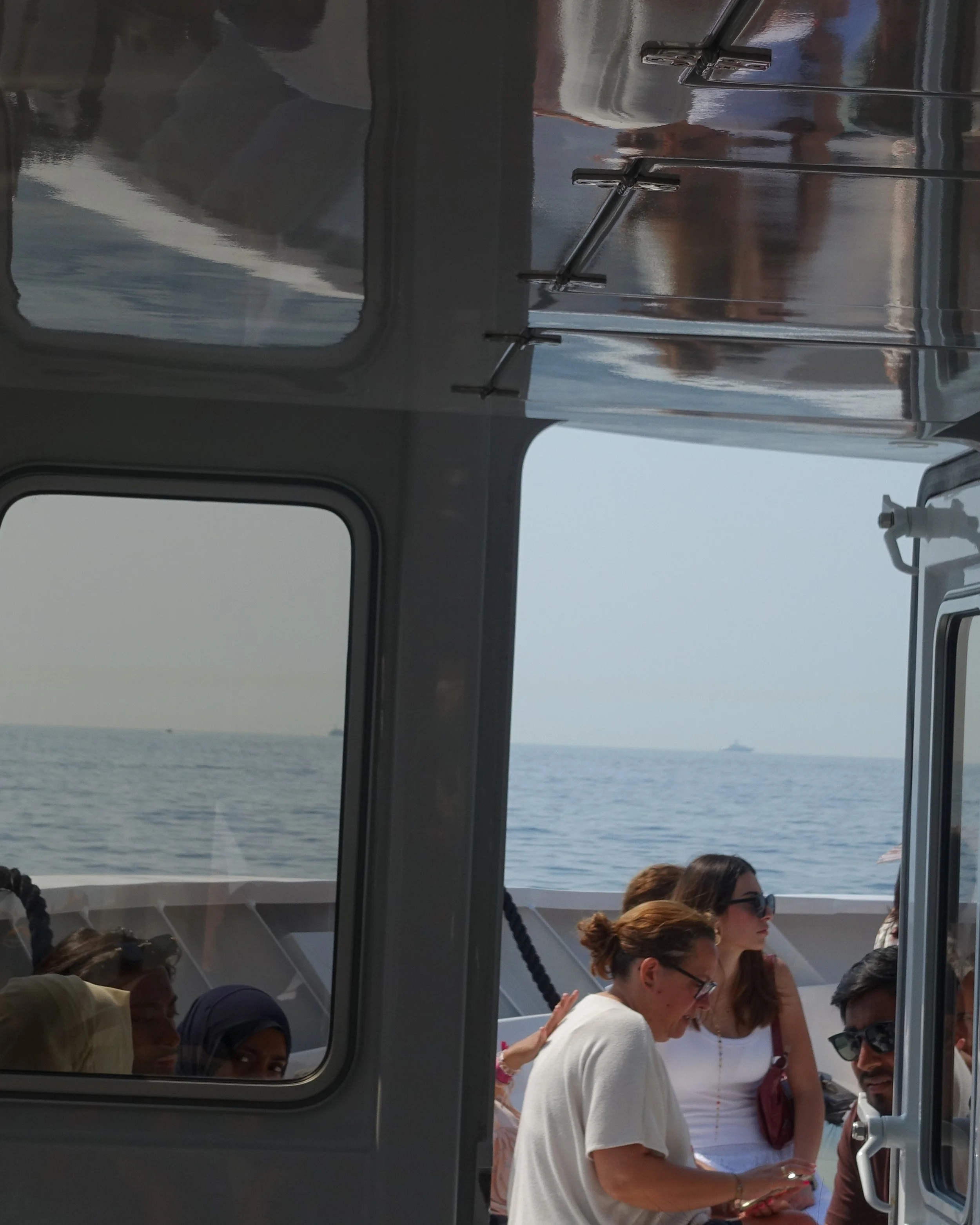 Groupe de personnes sur un bateau en mer, vue partielle à travers une fenêtre.