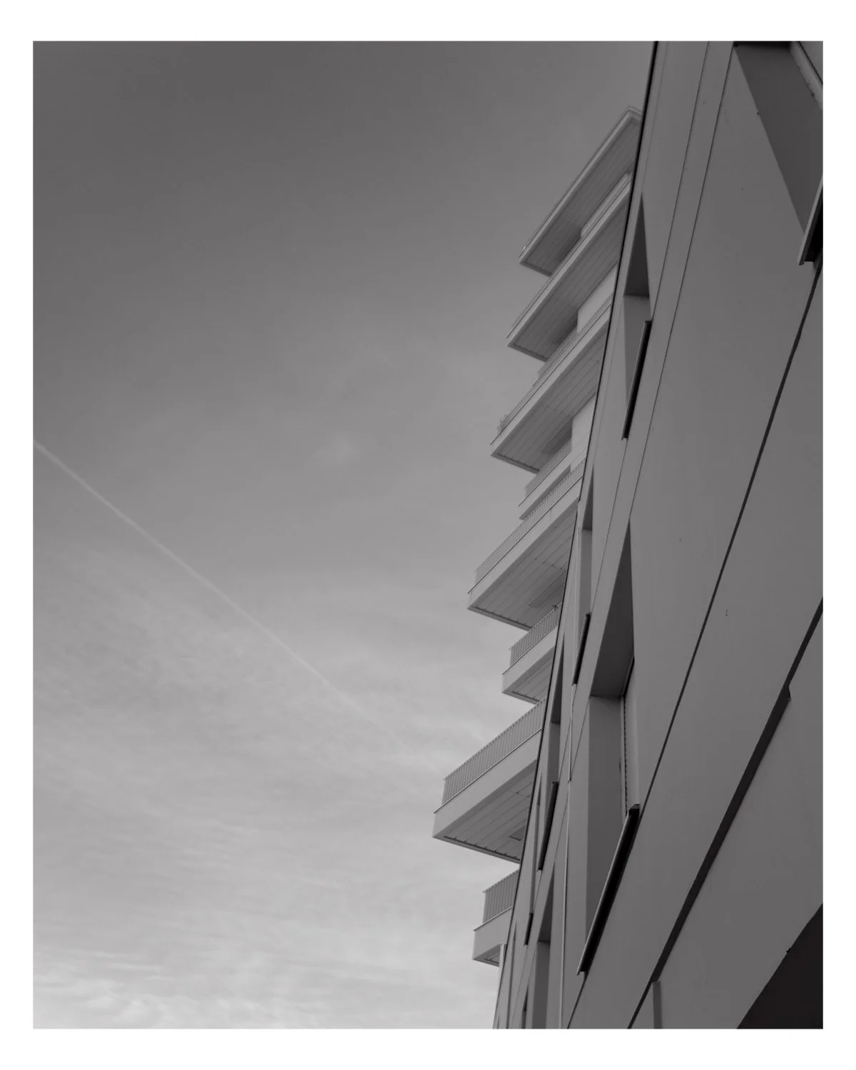 Vue en plongée d'un bâtiment moderne avec plusieurs balcons, photo en noir et blanc.