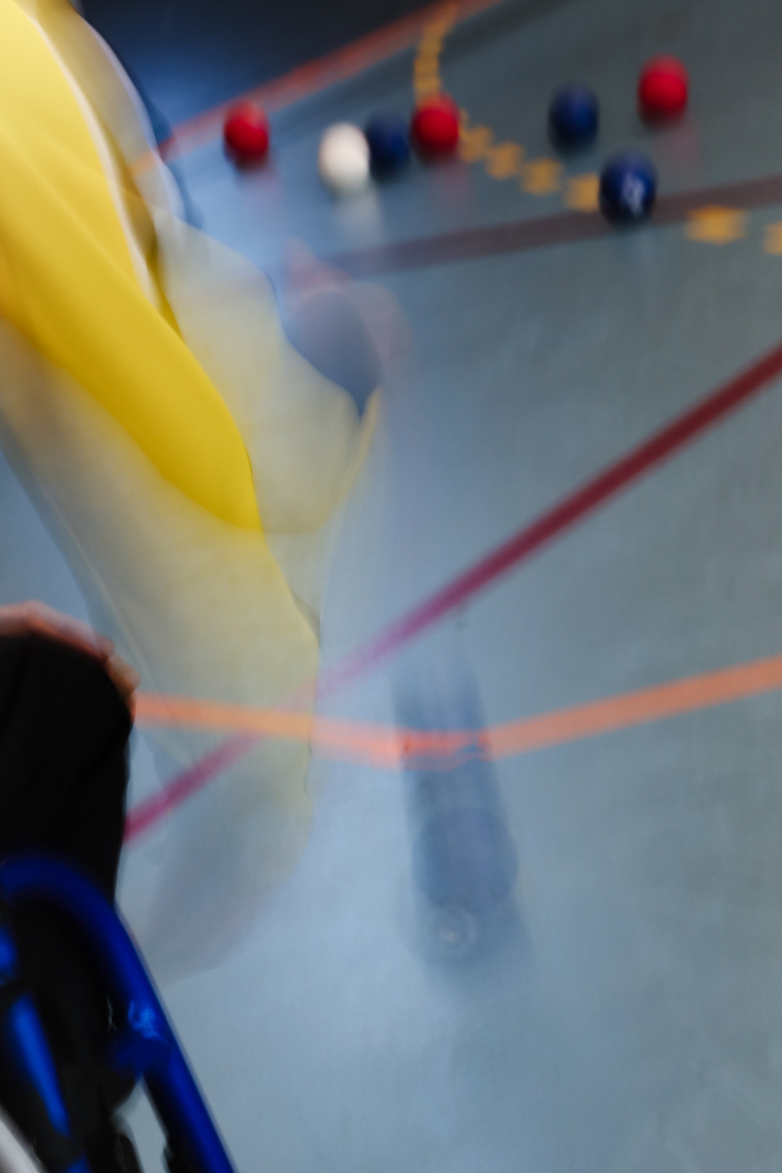 Une personne en fauteuil roulant joue à un jeu de fléchettes sur un mur avec des fléchettes colorées et une surface de jeu.