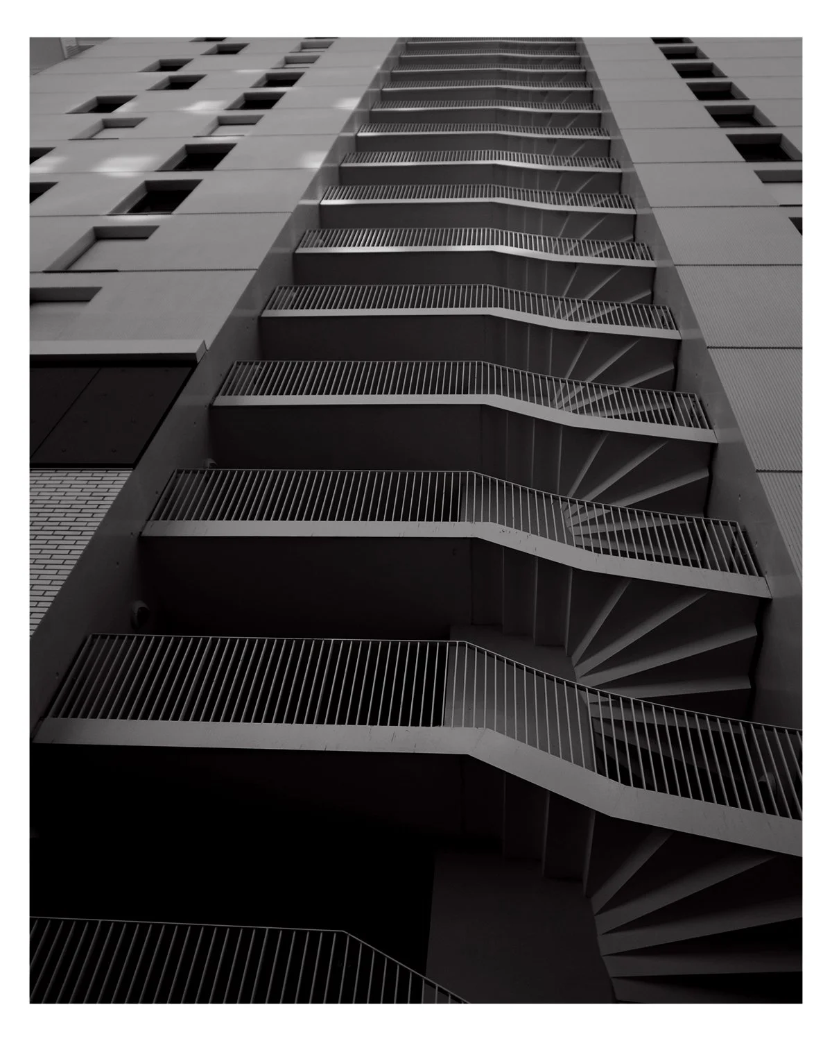 Un immeuble moderne avec un escalier de secours en colimaçon vu de bas en haut.