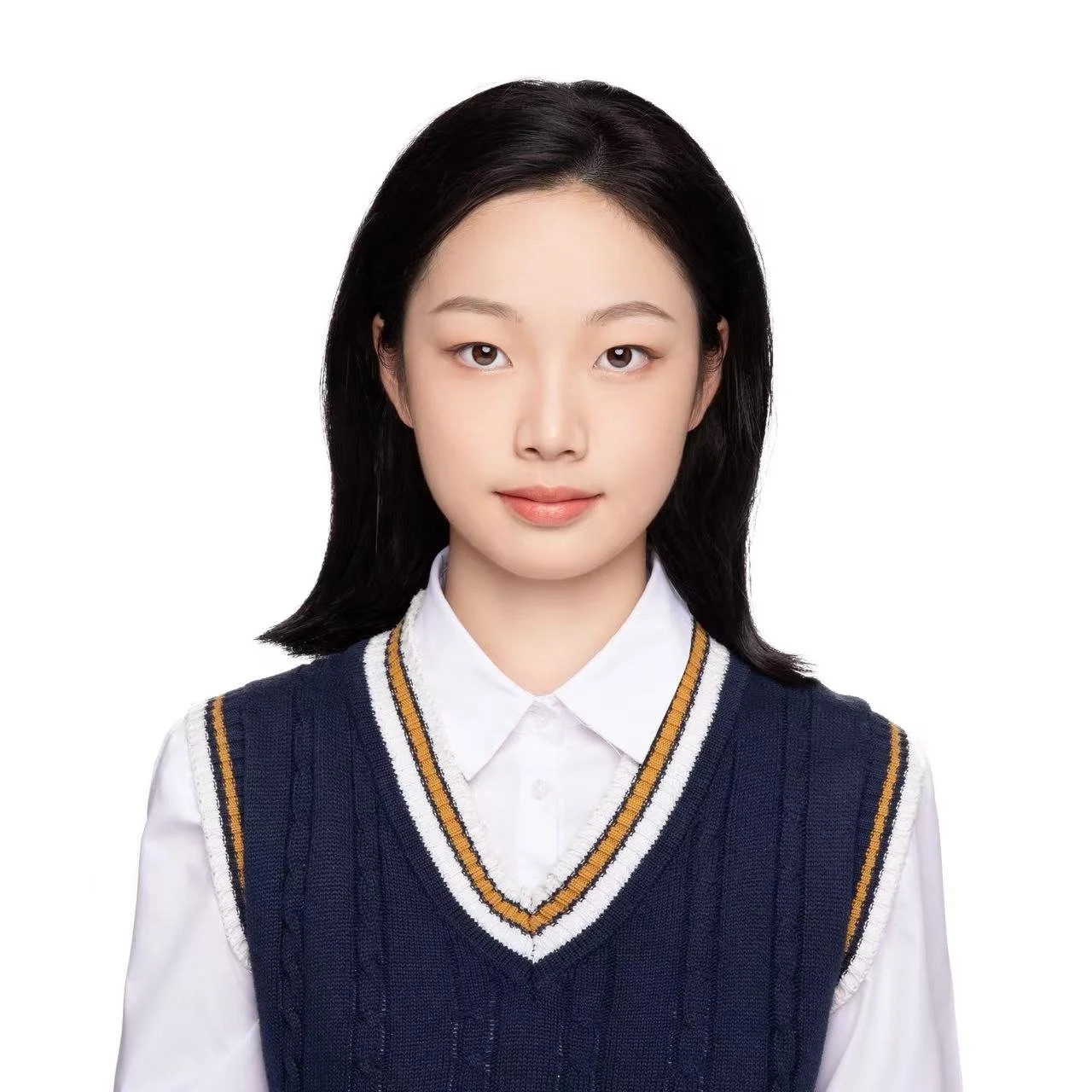 A young woman with black hair wearing a white collared shirt and a navy blue sweater vest with white, yellow, and navy stripes.