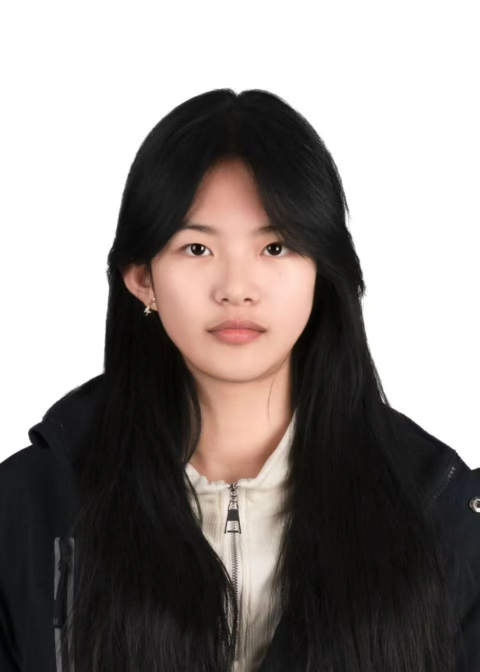 Headshot of a young woman with long black hair, wearing a black jacket and a white zip-up top against a plain white background.