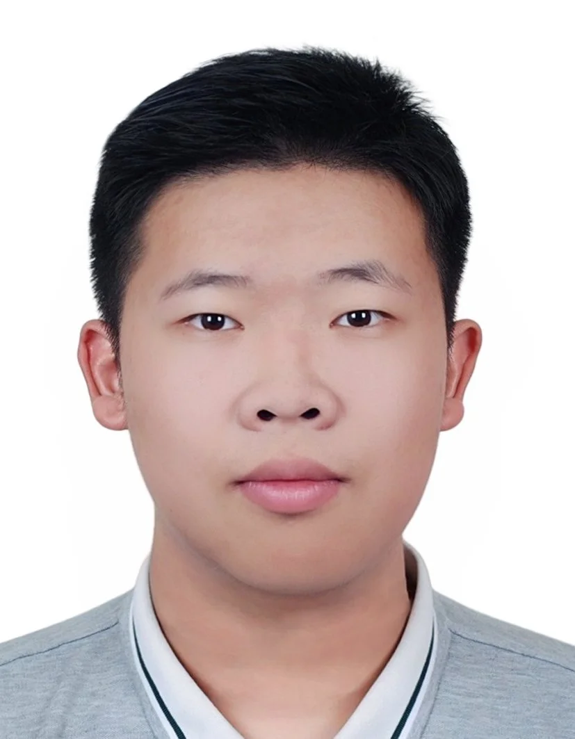 Headshot of a young Asian man with short black hair, wearing a gray shirt, against a plain white background.