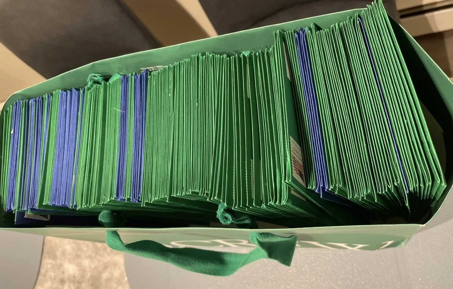 A green tote bag filled with numerous green and blue paper documents or folders.