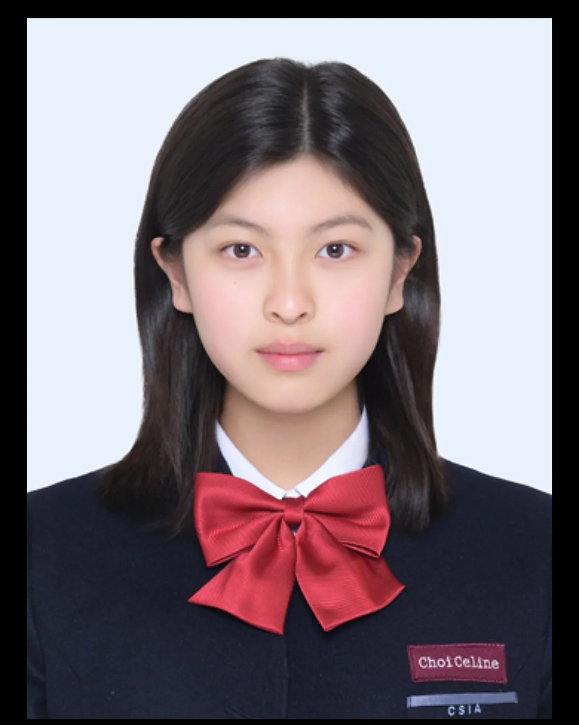 A young woman with straight, shoulder-length dark hair, wearing a black school uniform with a white shirt underneath, a red bow tie, and a name tag that says 'Choi CheLae', against a light blue background.
