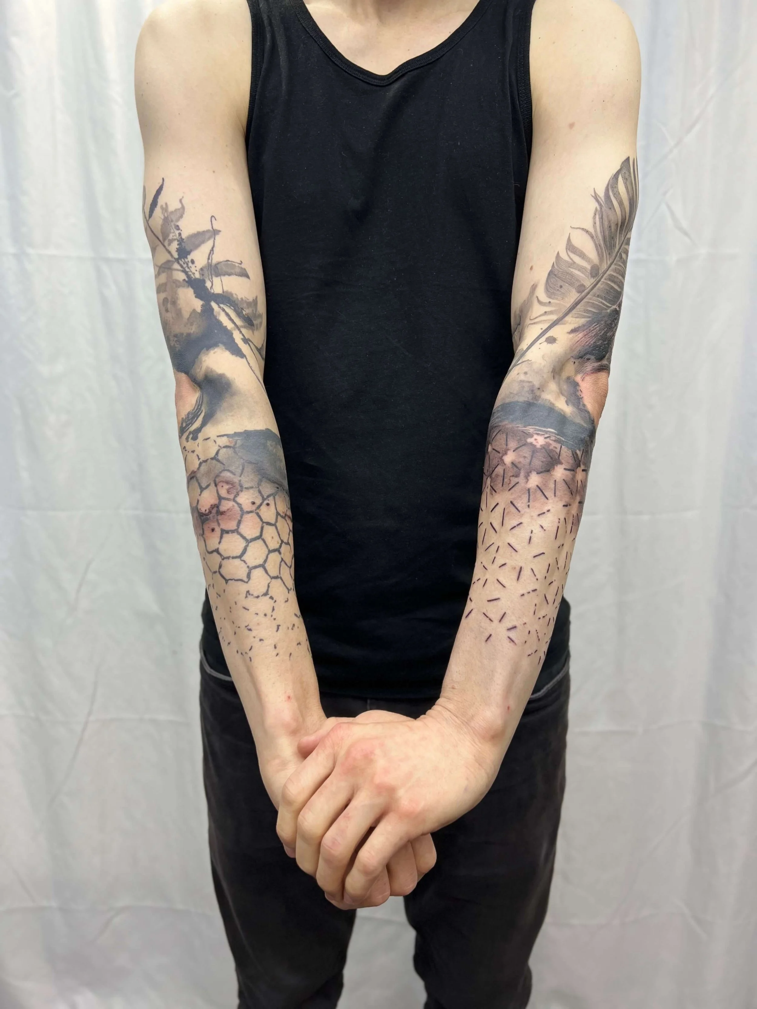 Blackwork sleeve tattoos featuring detailed illustrative compositions on both arms.