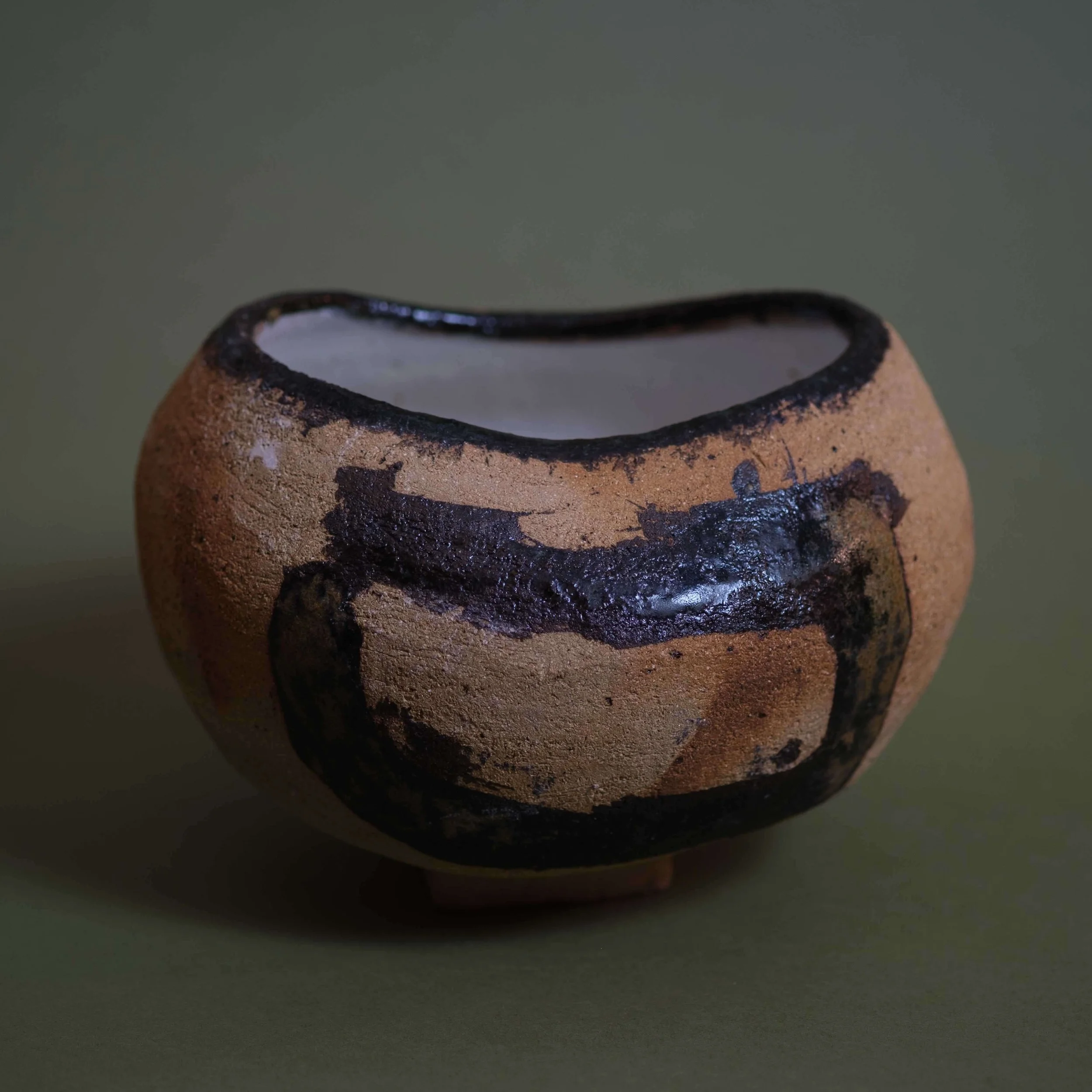 Side view of Trace sculptural pottery highlighting its low rounded shape and contrasting dark glaze patterns