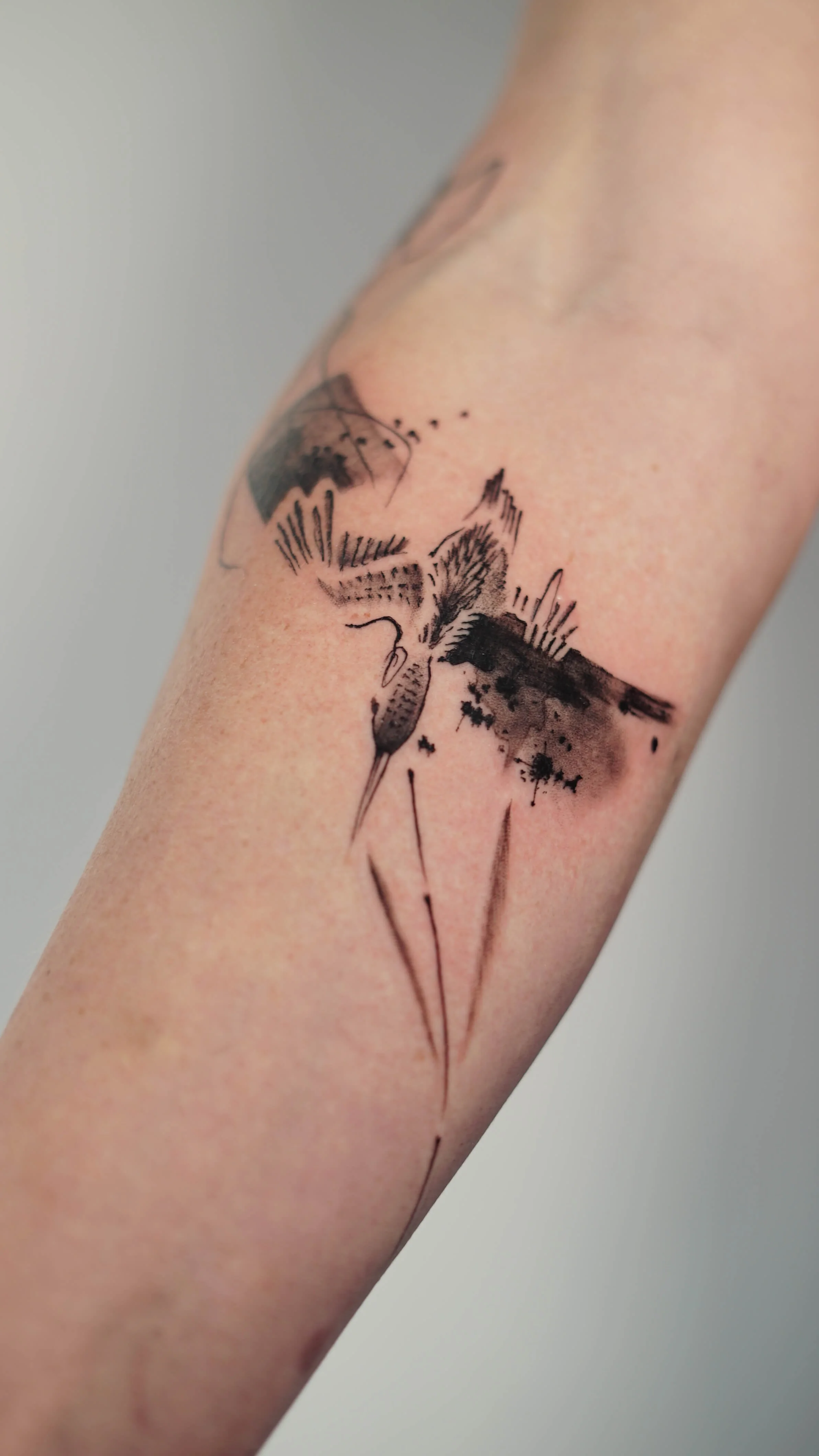 Contemporary abstract hummingbird tattoo combining black linework and fluid ink-style details.