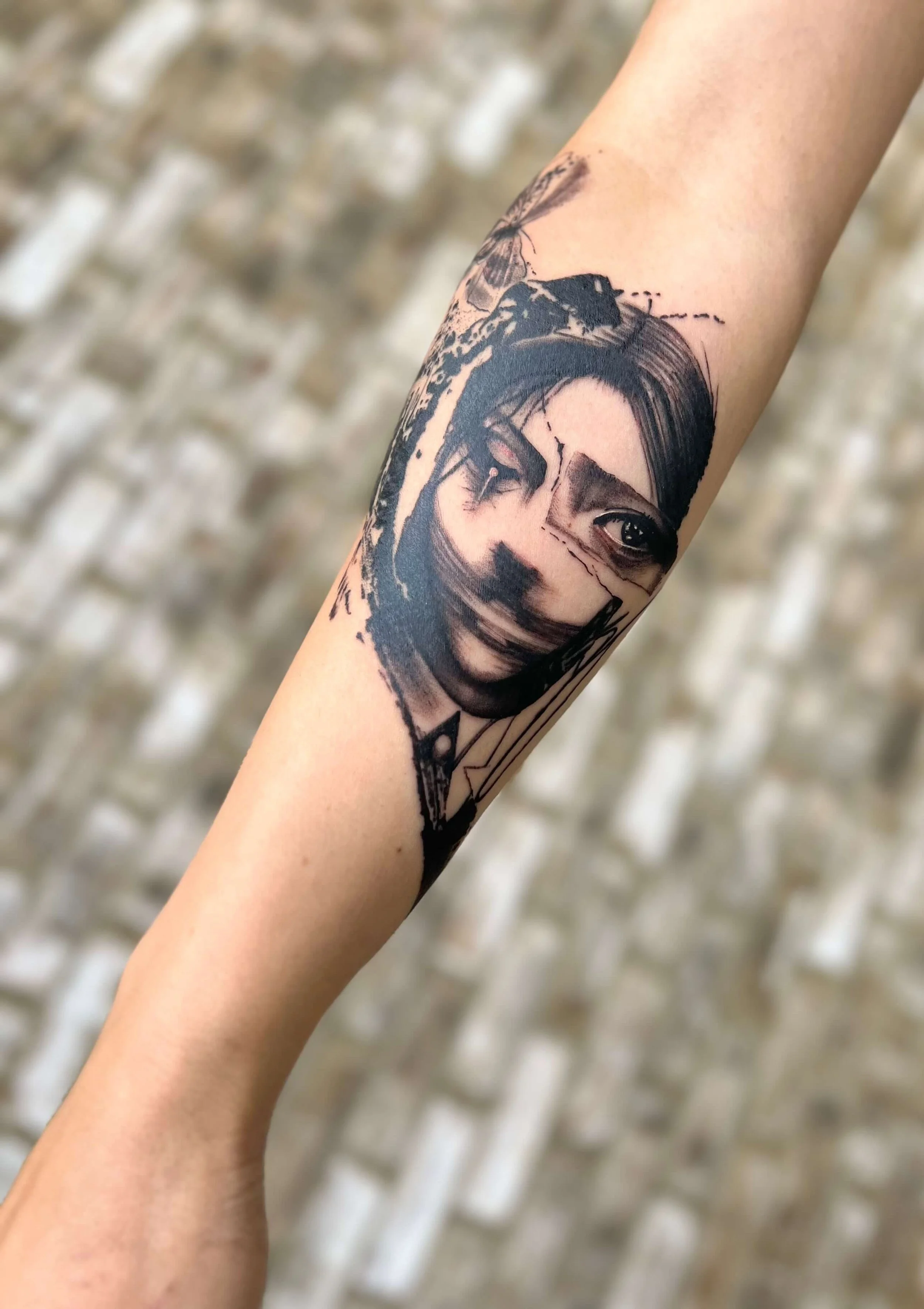 Abstract black ink portrait tattoo on the forearm with sketch-inspired linework and expressive structure.