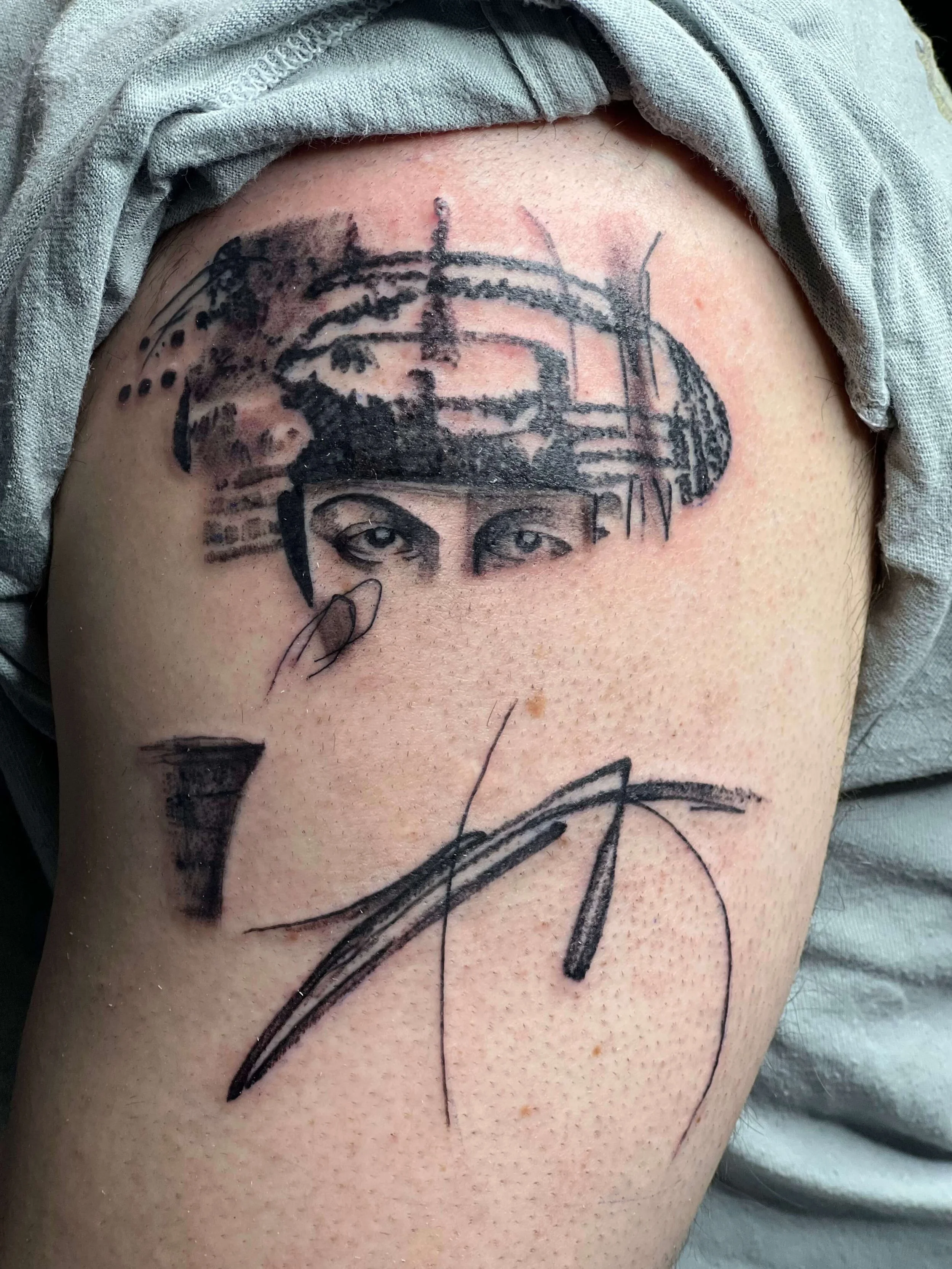 Abstract black ink upper arm tattoo featuring detailed eye imagery with geometric and expressive line elements.