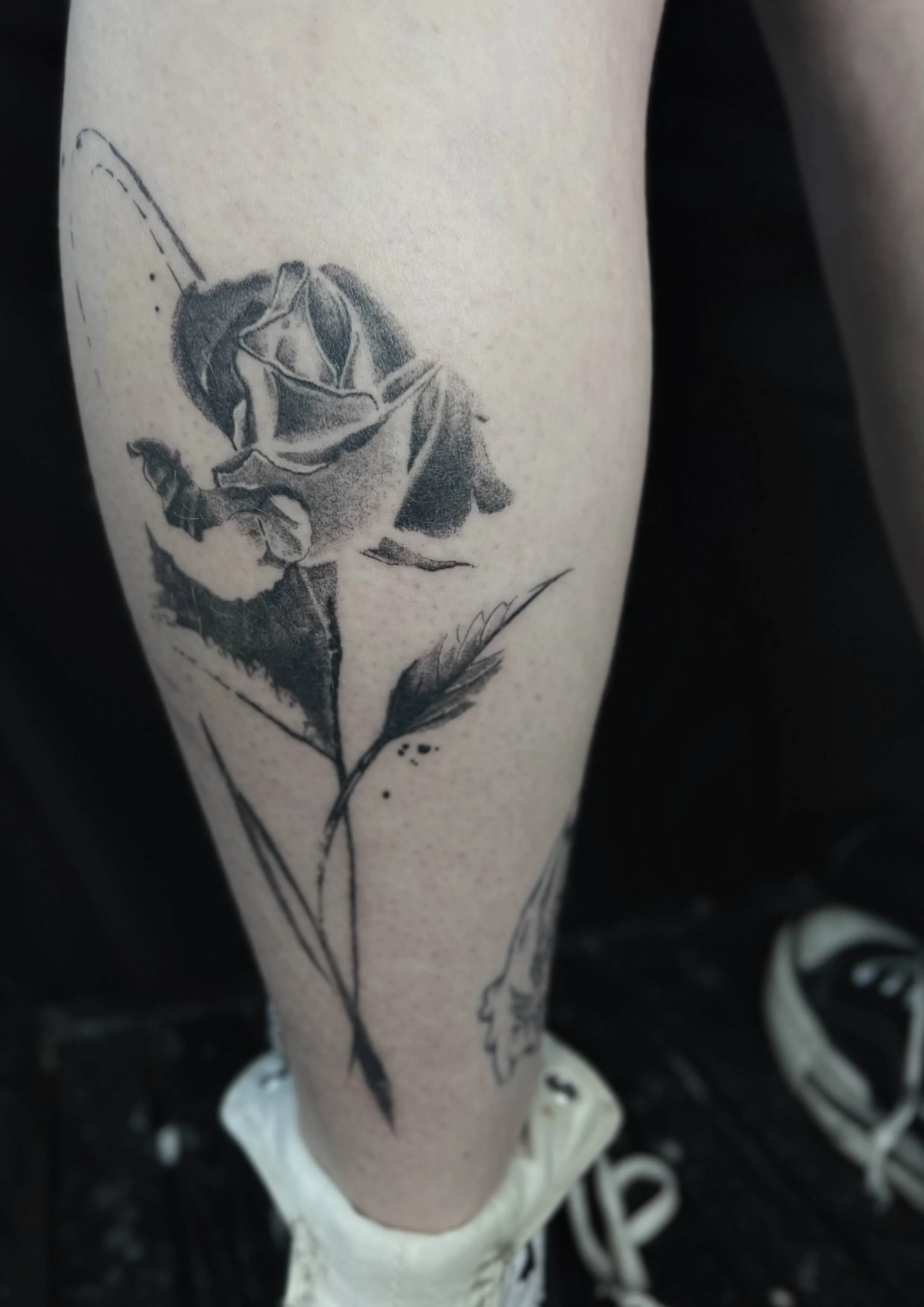 Black and grey rose tattoo with soft shading and fine line detail.