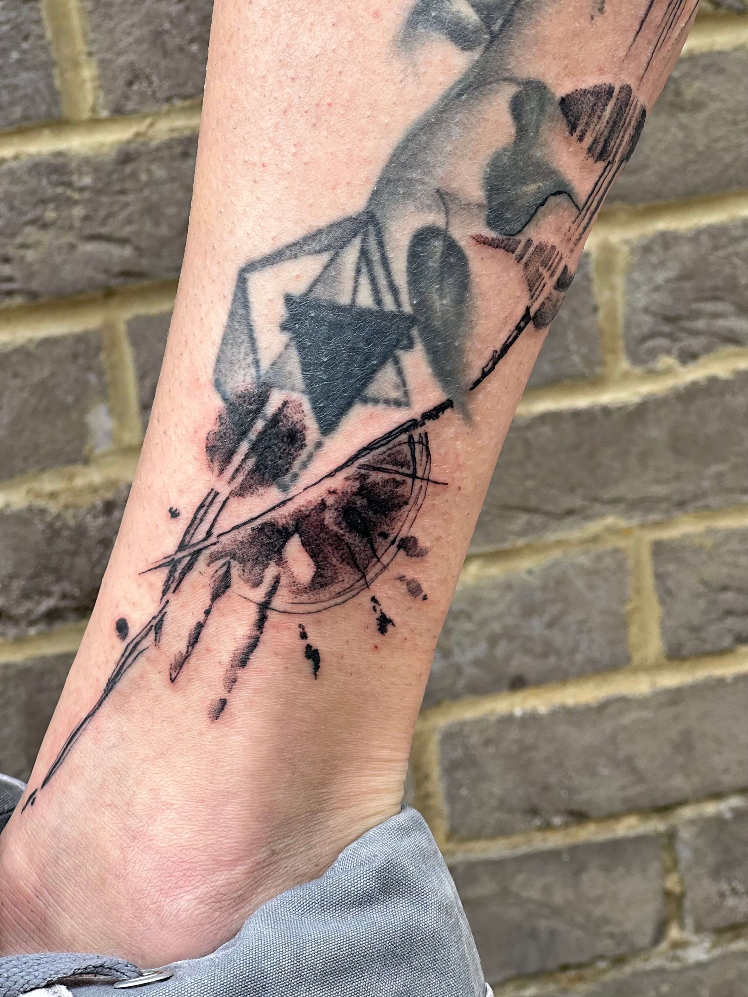 Tattoo of a abstract ink splatters on a person's forearm.