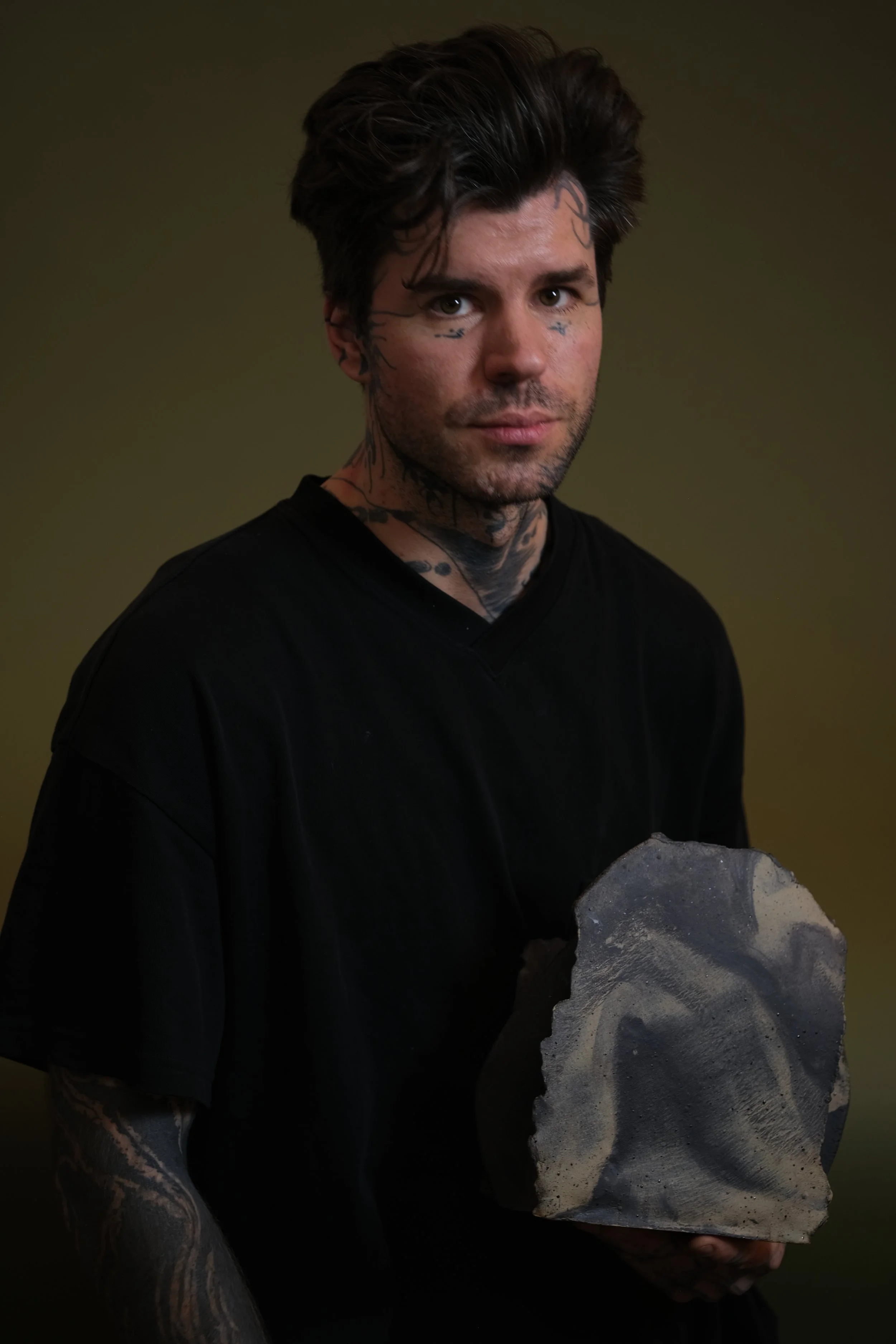 Portrait of a London-based tattoo artist holding a sculptural ceramic piece against a neutral background.