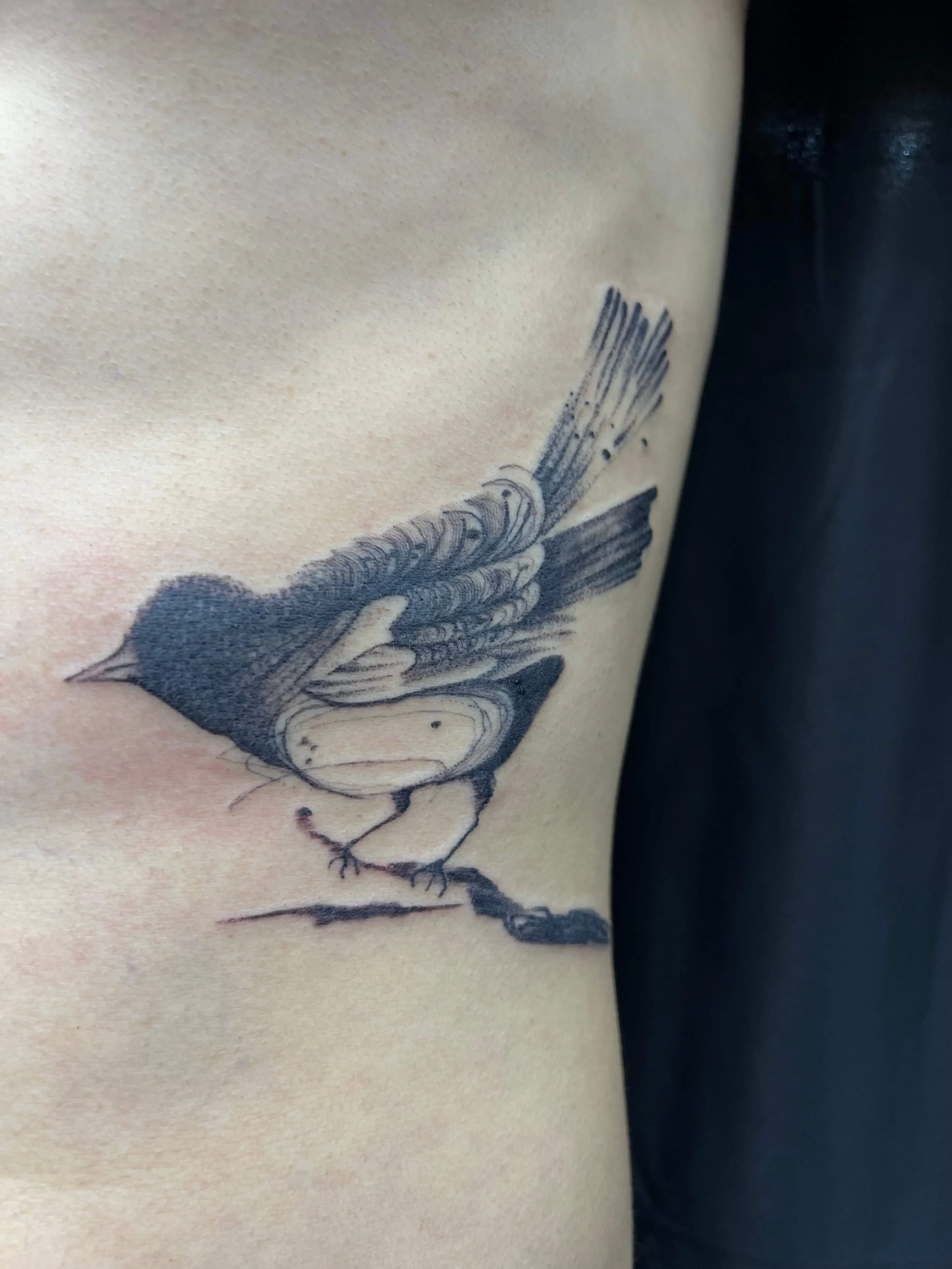 Abstract black and grey side tattoo featuring bird-inspired imagery with refined linework.