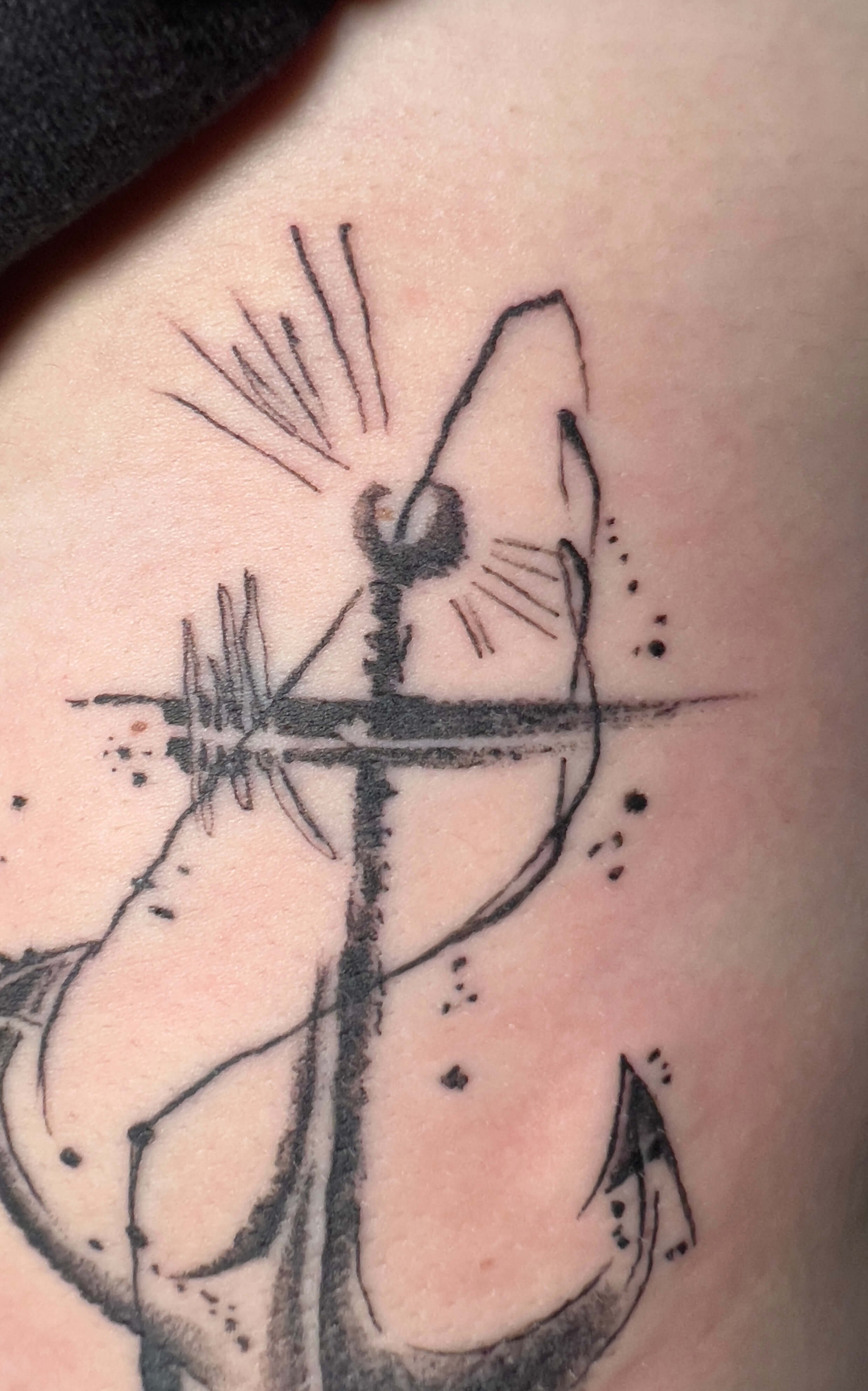 Abstract blackwork anchor tattoo with expressive sketch-style linework and ink splatter detailing.