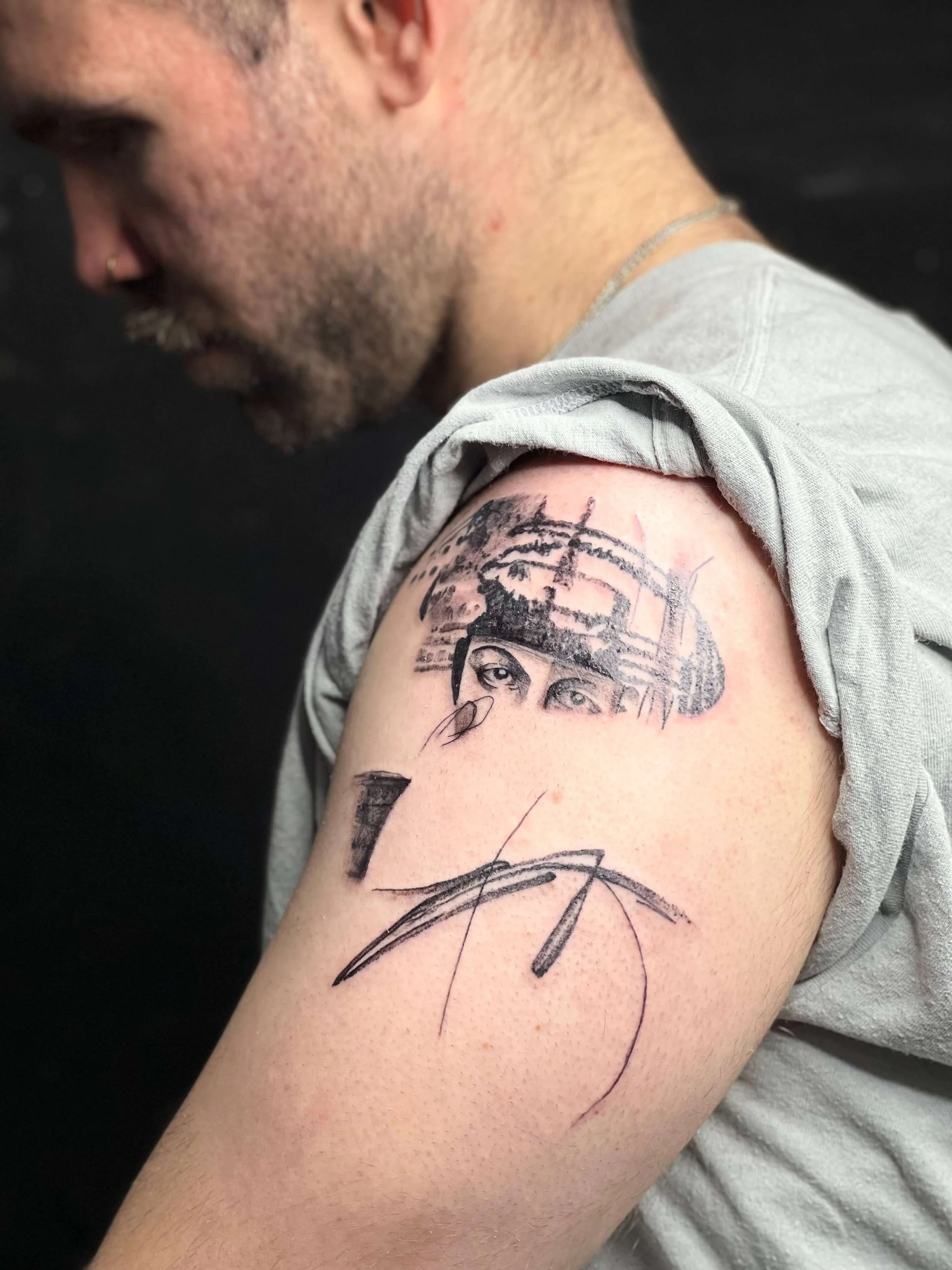 Contemporary black ink upper arm tattoo combining figurative eye imagery with expressive abstract linework.