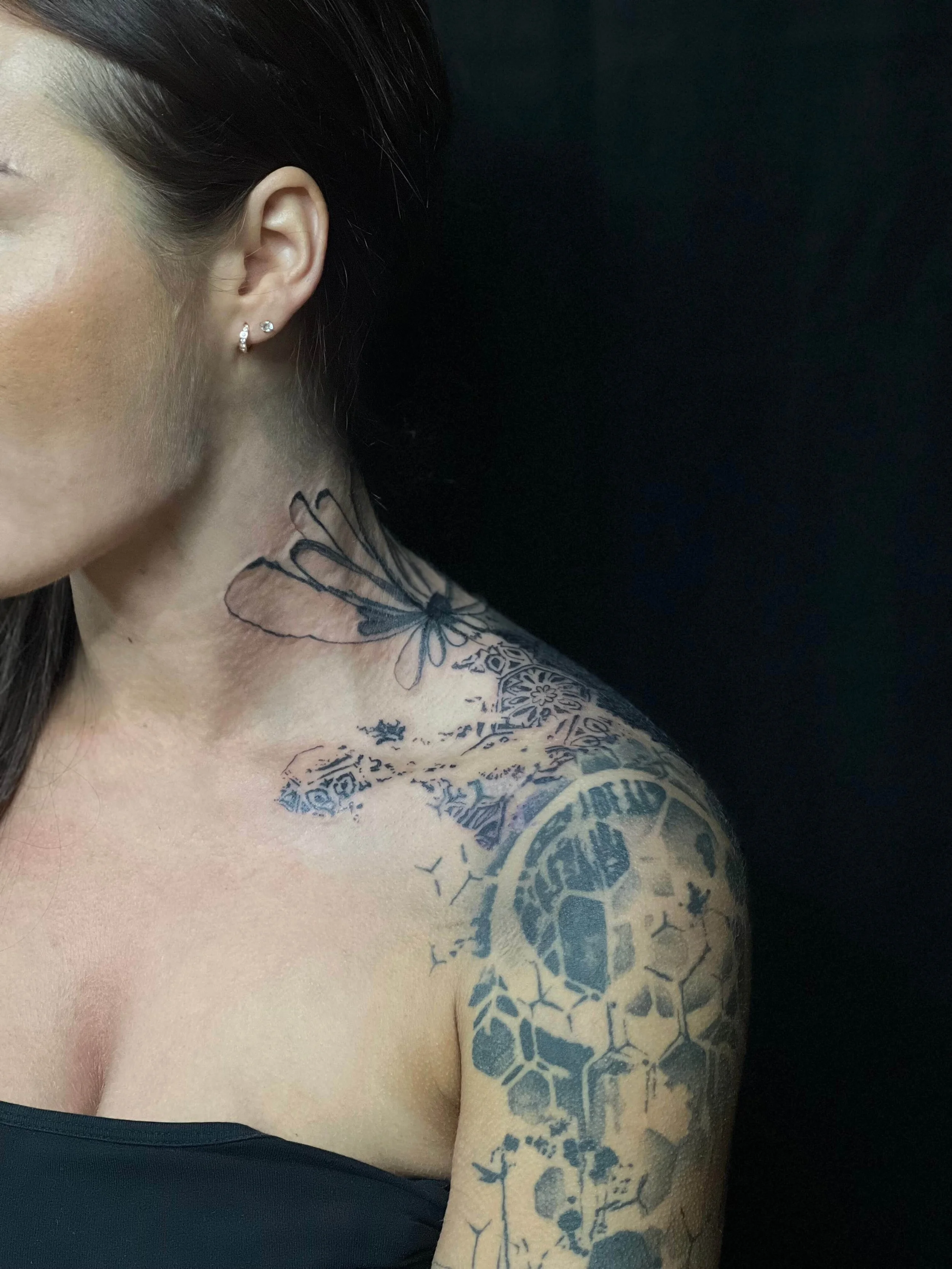 Detailed abstract tattoo composition across the shoulder and upper arm with layered black ink linework.