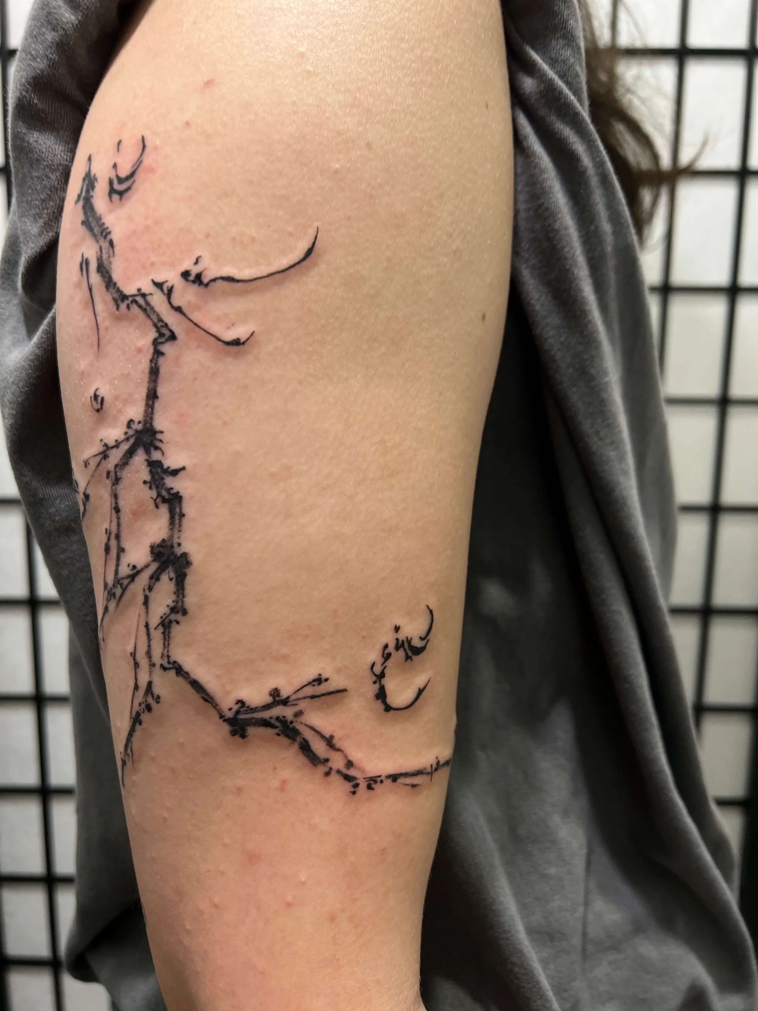 Minimal abstract linework tattoo on the upper arm inspired by constellation forms and geometric structure.