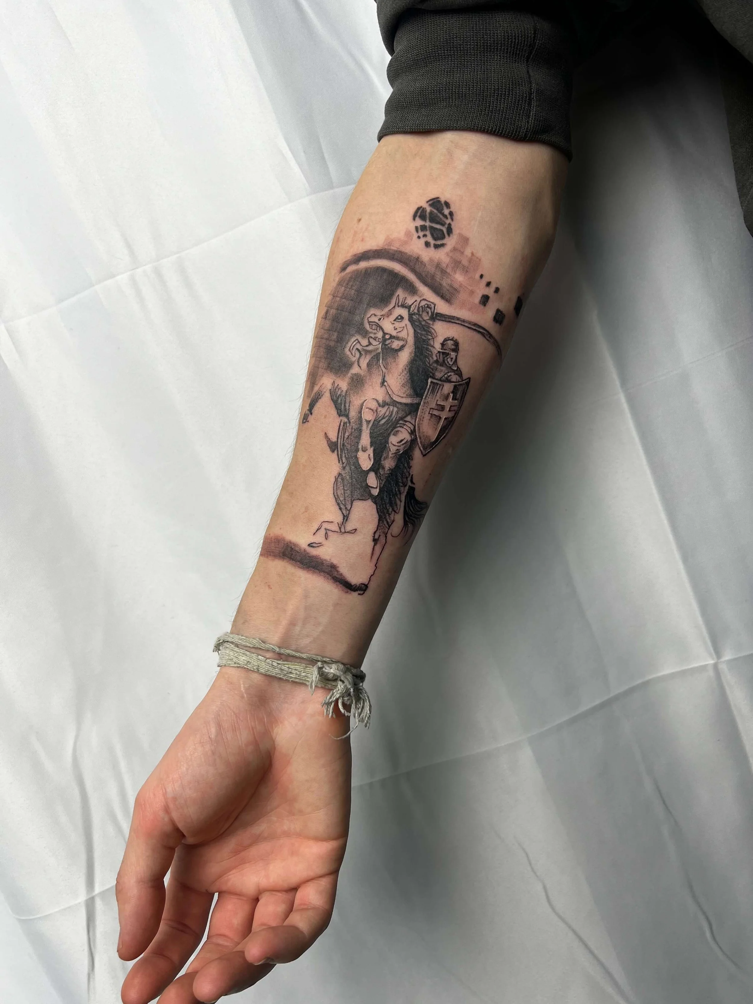 Large-scale black and grey knight composition with mounted figure and shield motif in detailed illustrative blackwork.