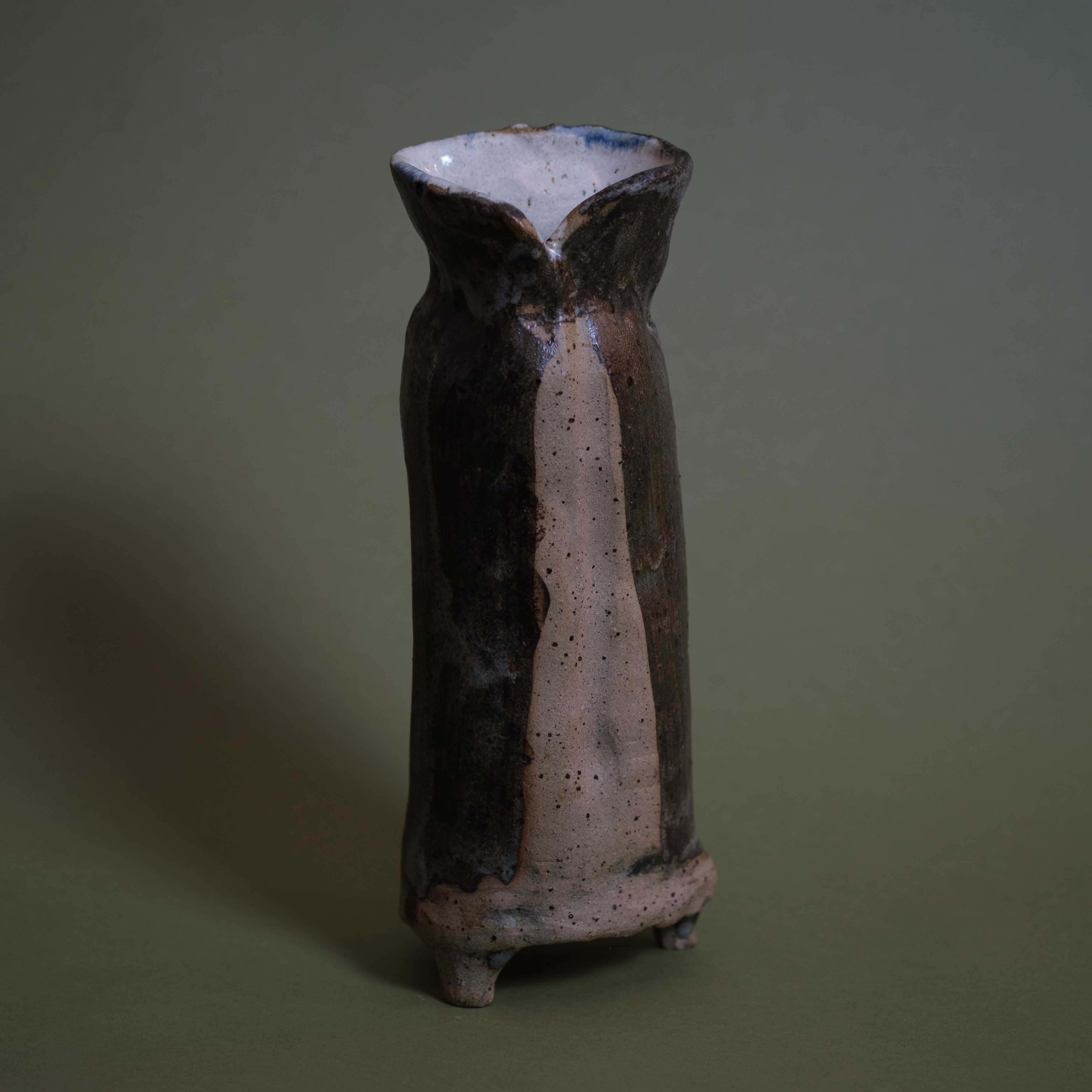 Side view of Tall Green Vessel sculptural pottery highlighting its elongated silhouette and dark green glaze variations