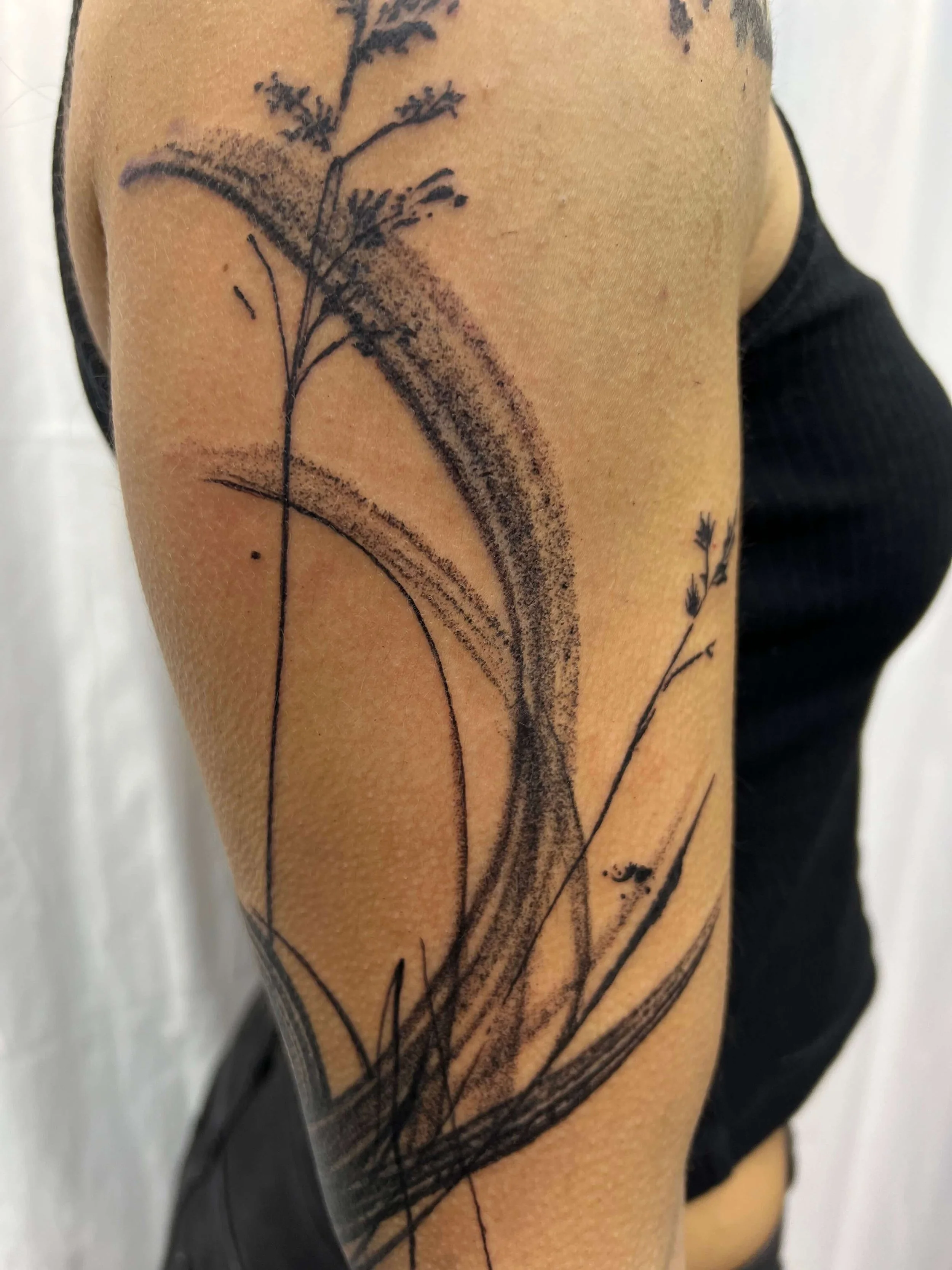 Abstract blackwork tattoo featuring expressive ink strokes and flowing botanical linework.
