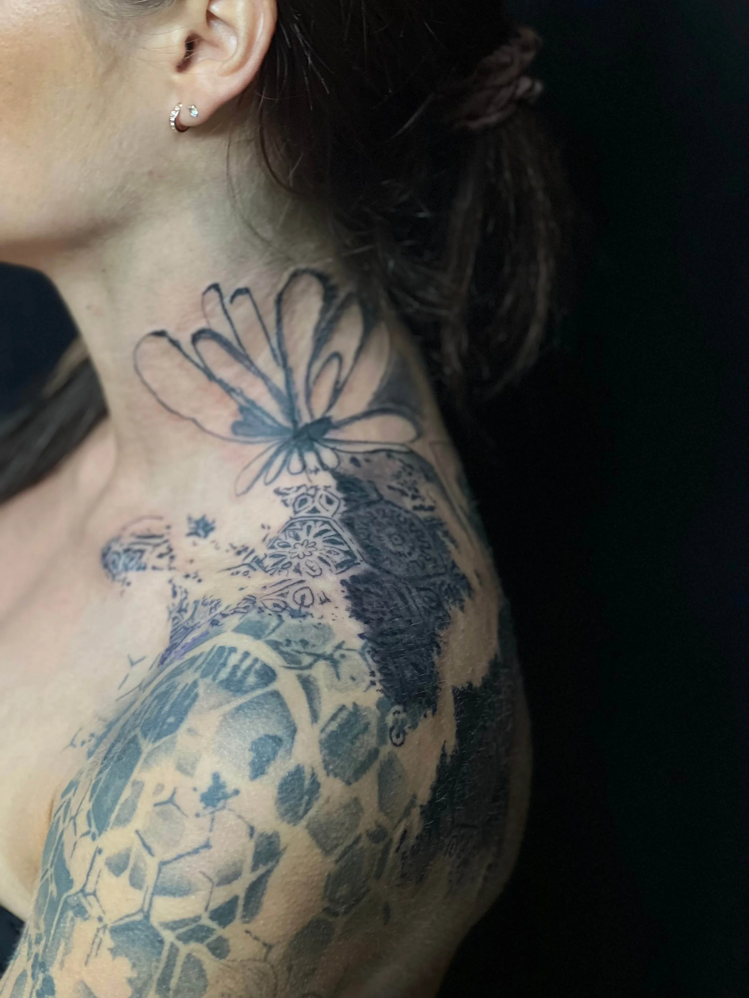 Large abstract tattoo composition across the shoulder and neck combining organic forms and detailed linework.
