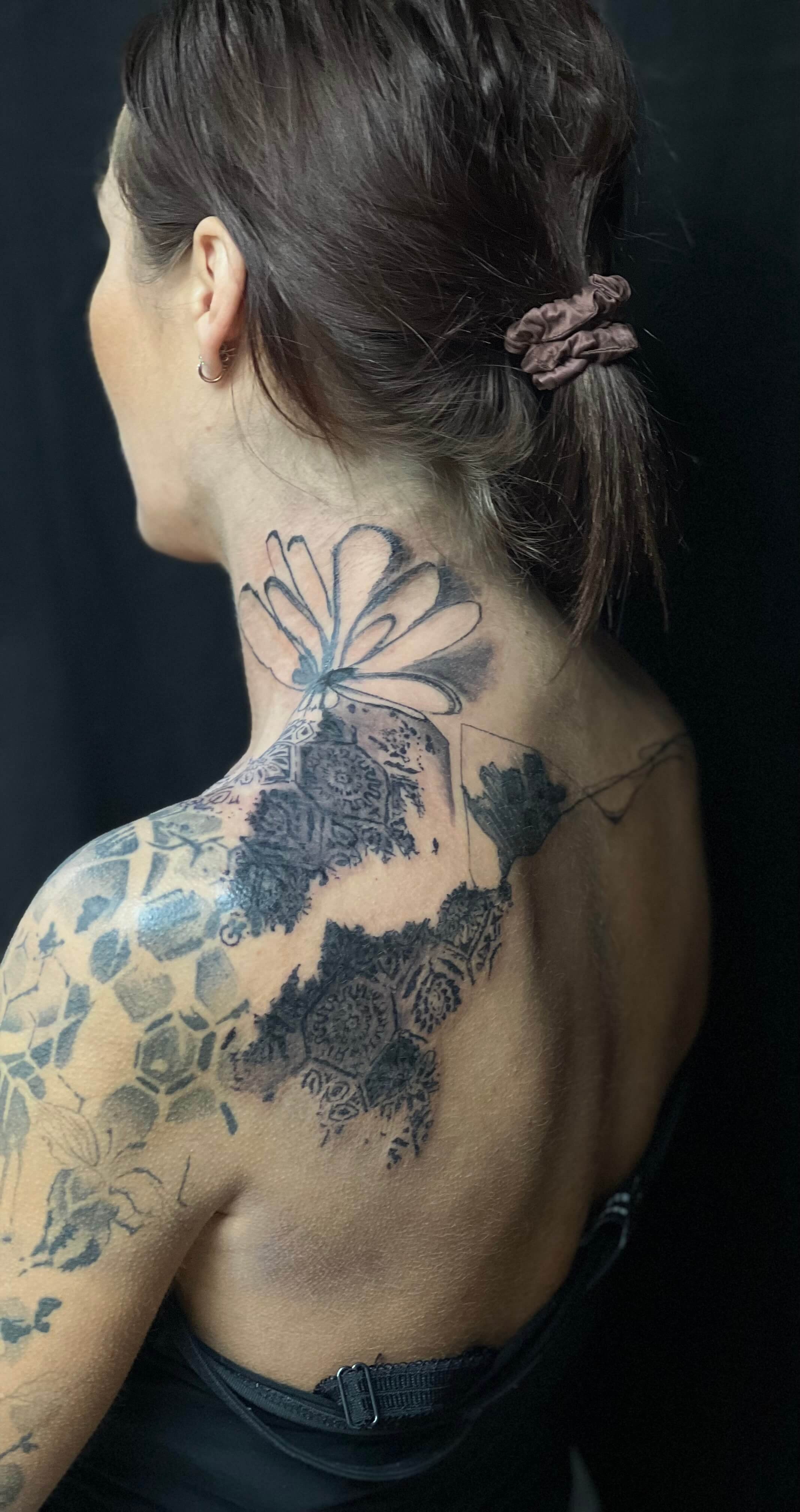 Abstract black ink tattoo sleeve on the shoulder and upper arm blending structural and fluid design elements.