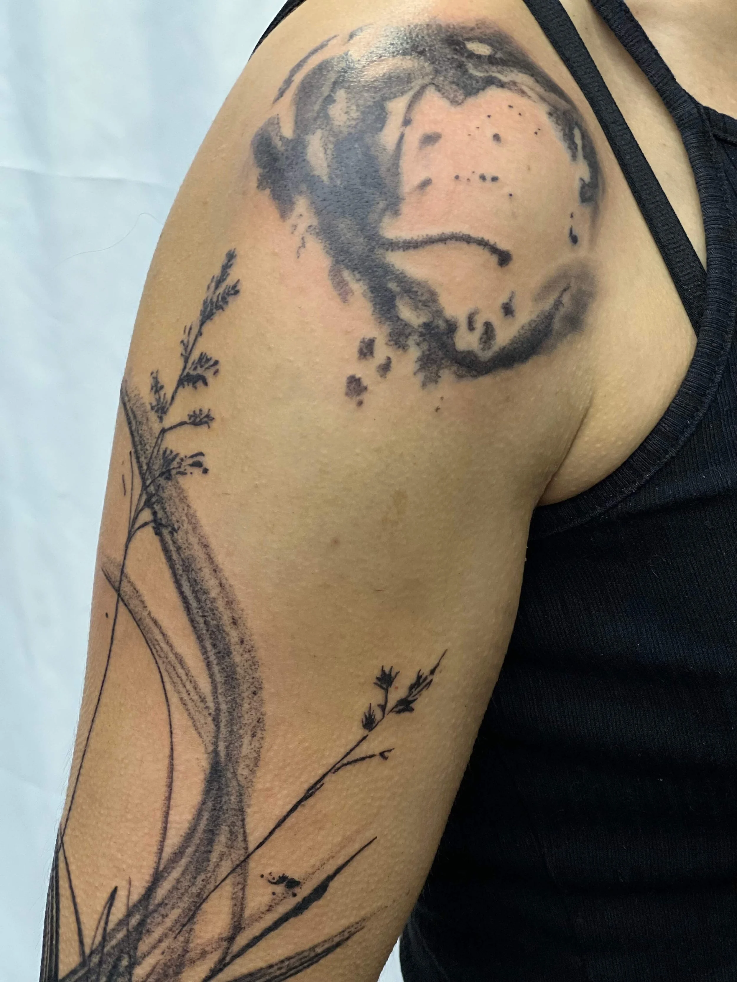 Black and grey portrait tattoo blended with flowing botanical elements in expressive ink style.