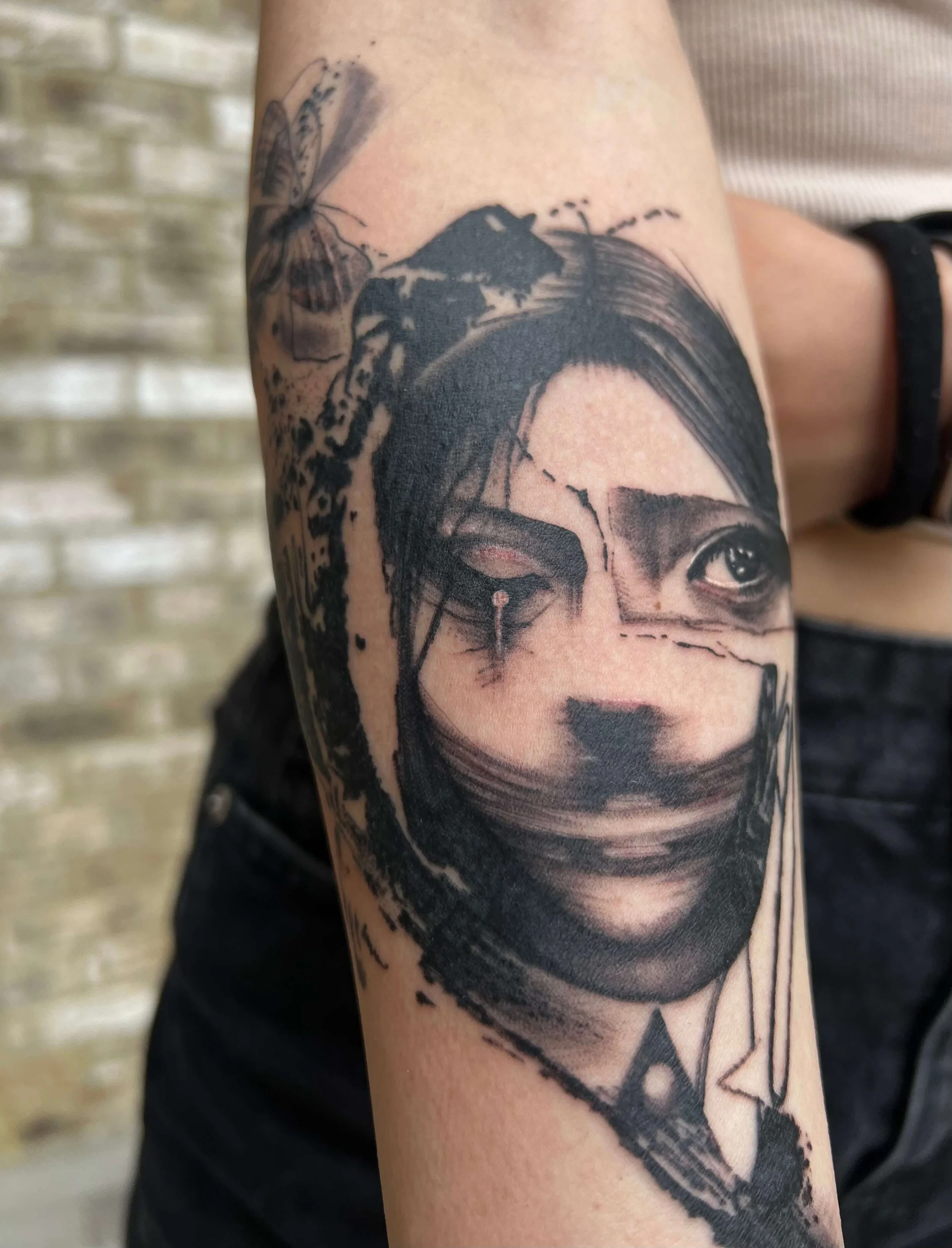 Abstract black and grey portrait tattoo combining figurative elements with expressive graphic detailing.