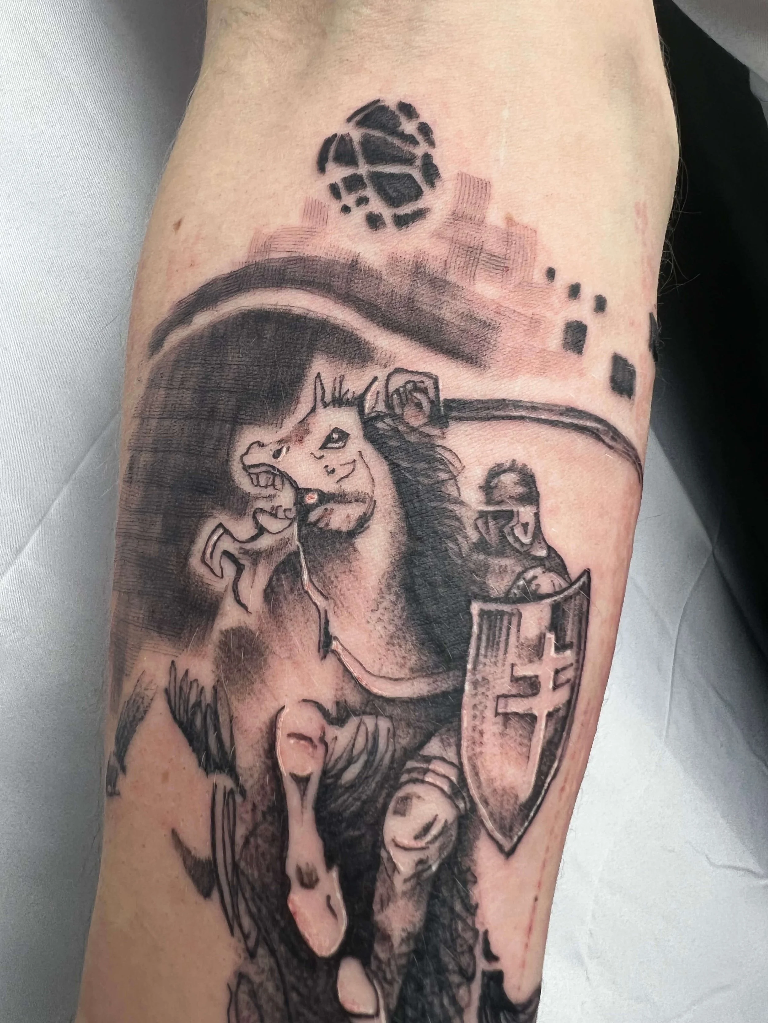 Black and grey knight-inspired tattoo with shield motif in contemporary illustrative style.